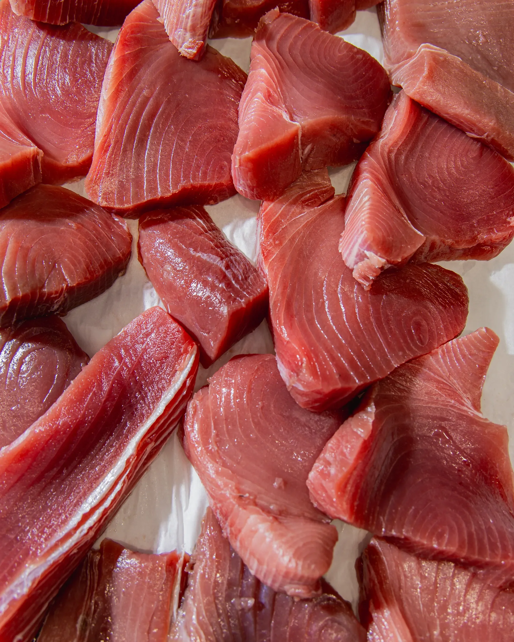 Close-up of raw tuna fish steaks with pinkish-red flesh and white fat lines.