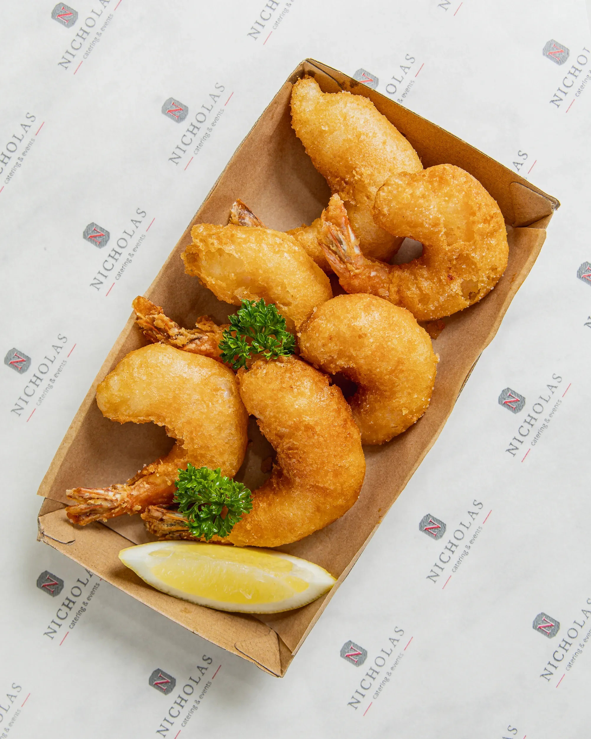 Fried shrimp and fried fish fillets garnished with parsley, served with a lemon wedge on a paper-lined tray.