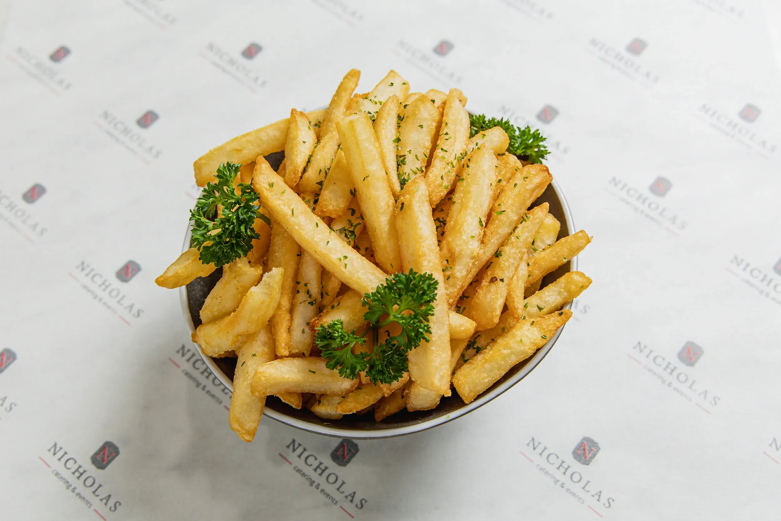 A bowl of French fries garnished with parsley.