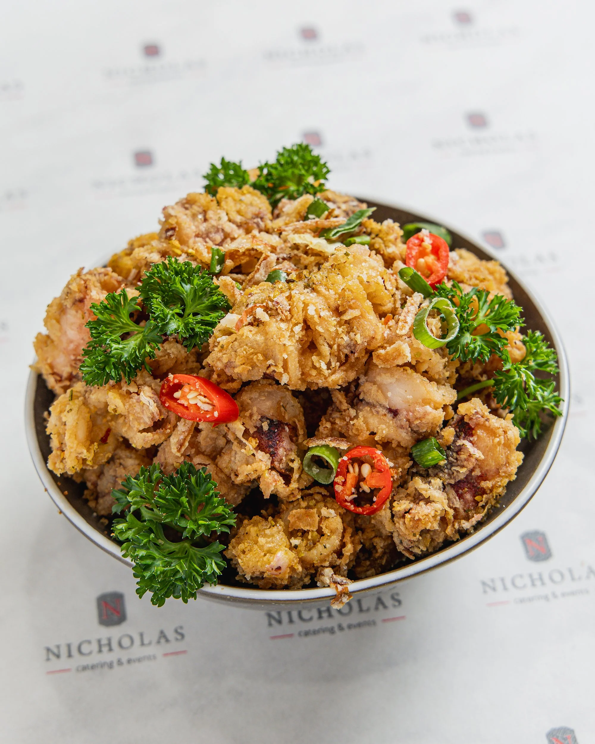 Fried chicken with red chili slices and parsley on a plate.