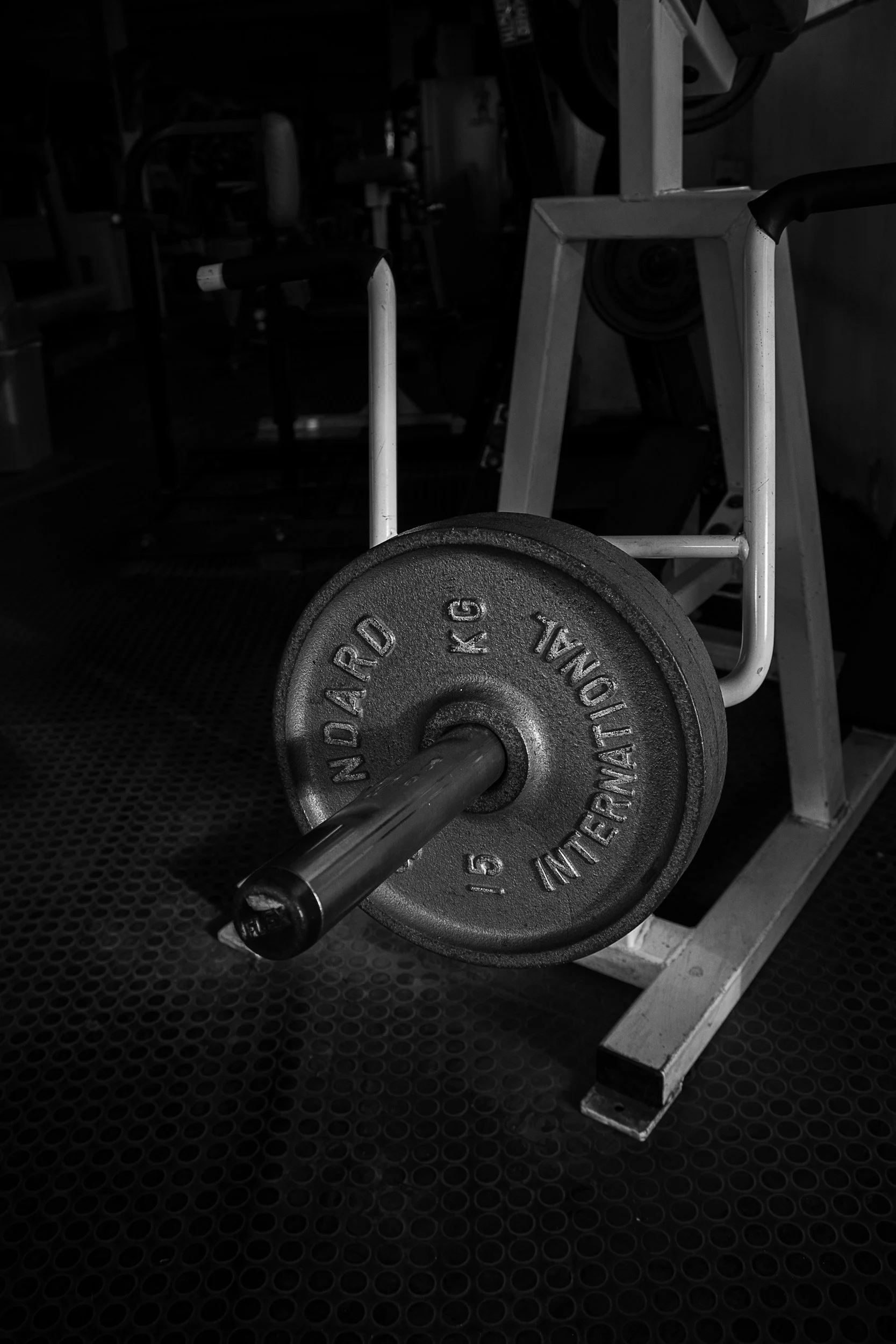 A single weight plate on a barbell resting on the floor of a gym.