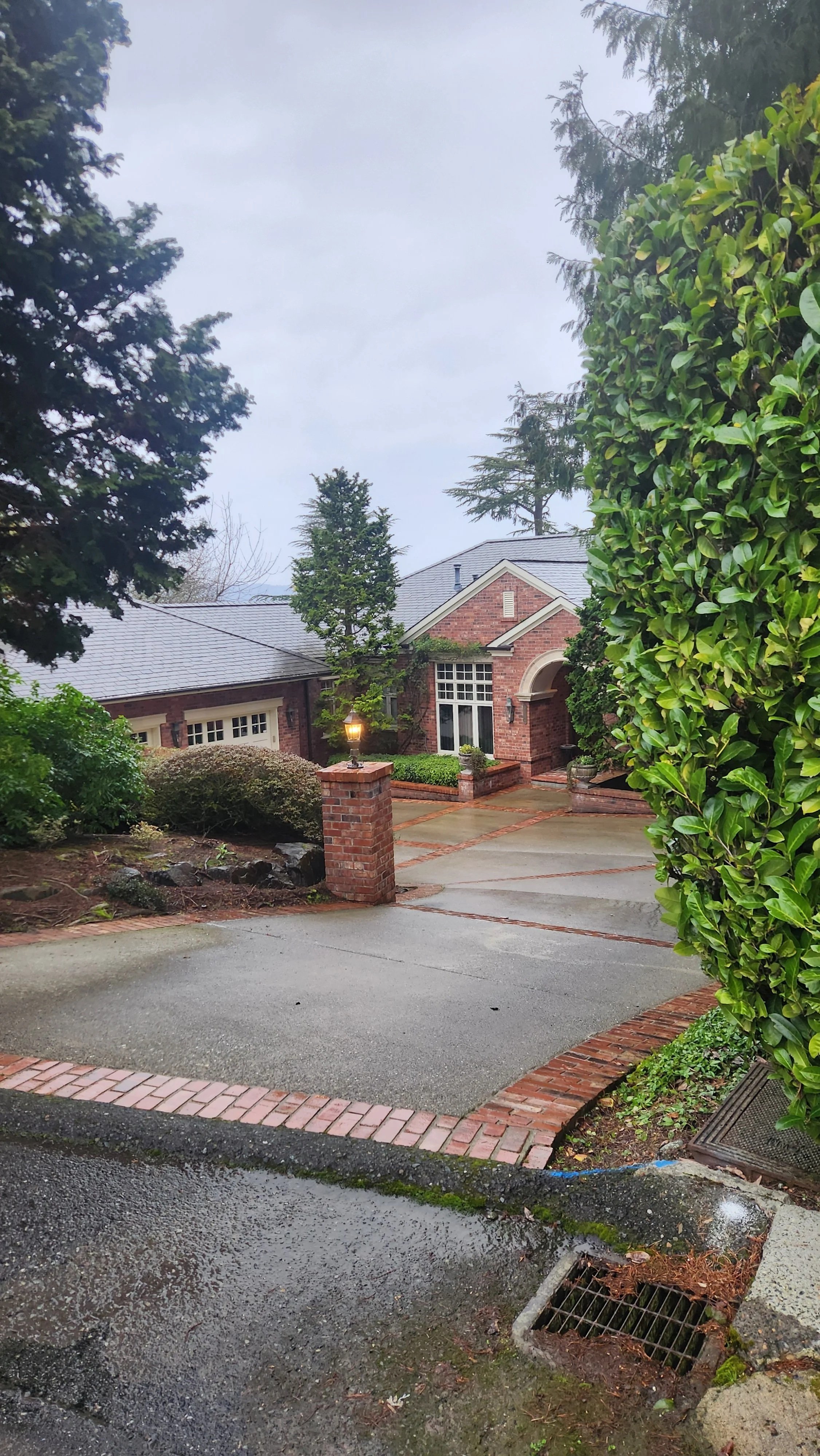 Professional cleaning of a paver driveway with integrated brick borders and site drainage management for a Seattle residence.