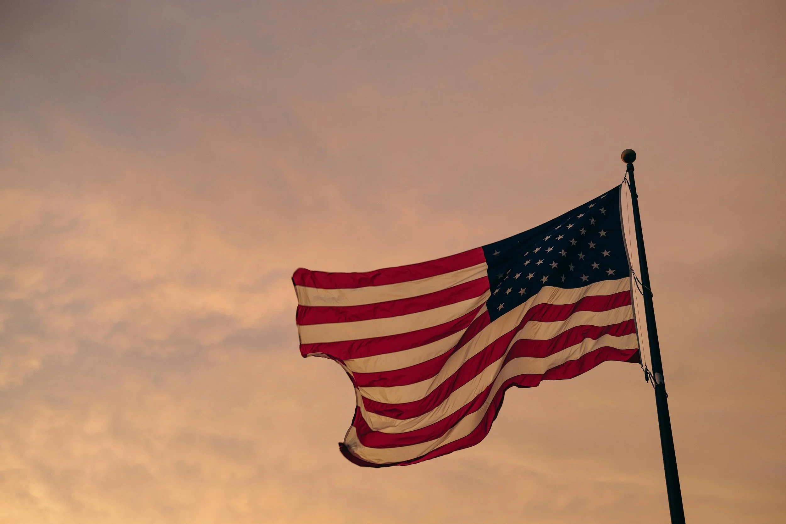 photo of USA flag against clouds at sunset