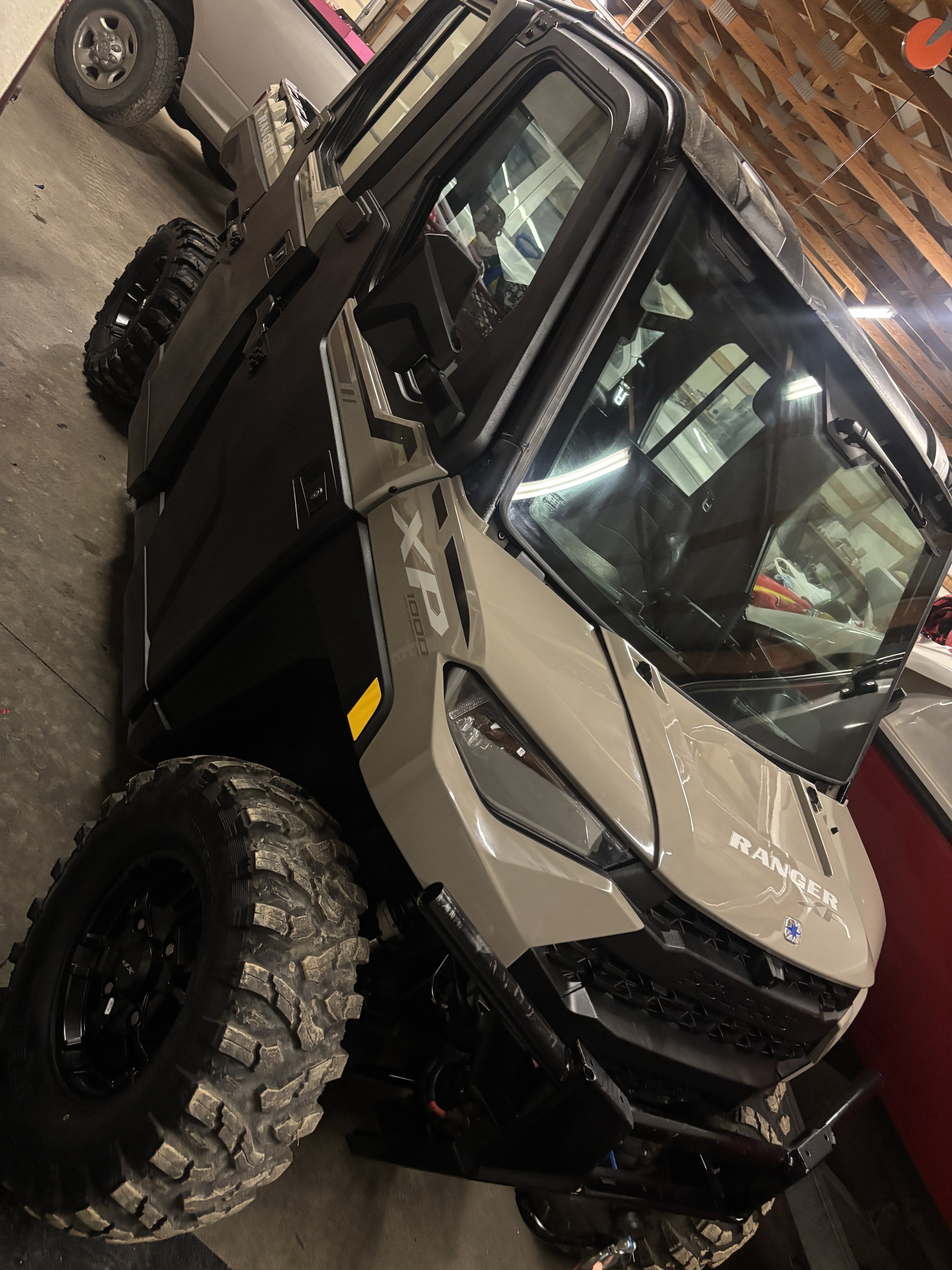 A beige and black Polaris Ranger XP 1000 off-road utility vehicle parked indoors.