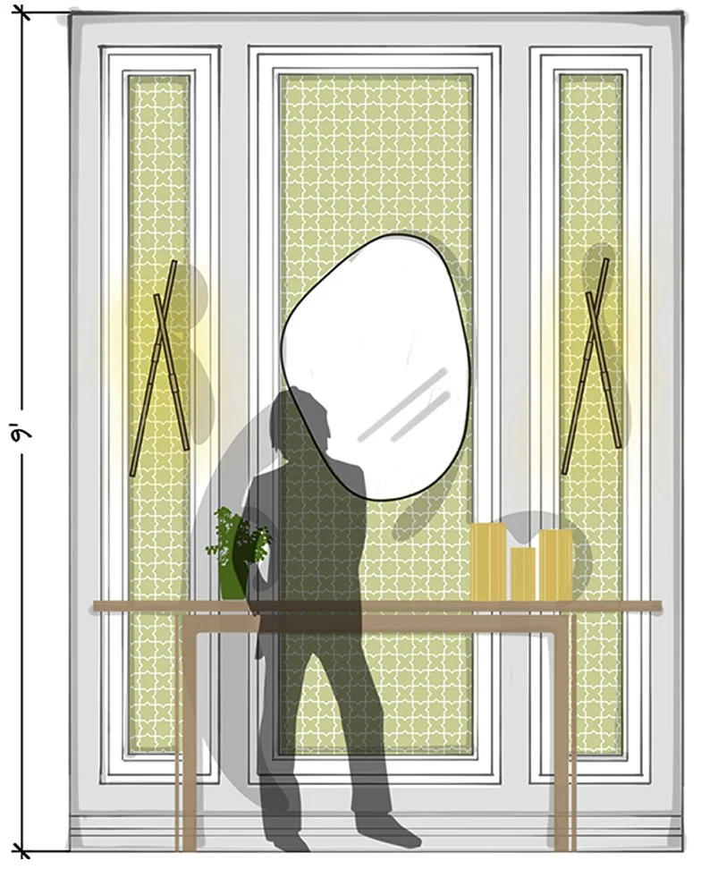 A person is taking a photo of a mirror with a smartphone in a decorated entryway or hallway with a table, plant, and books. The mirror is large and oval-shaped, mounted on a patterned wall. The room has two tall narrow windows with yellow or green curtains, and there's sunlight streaming in.
