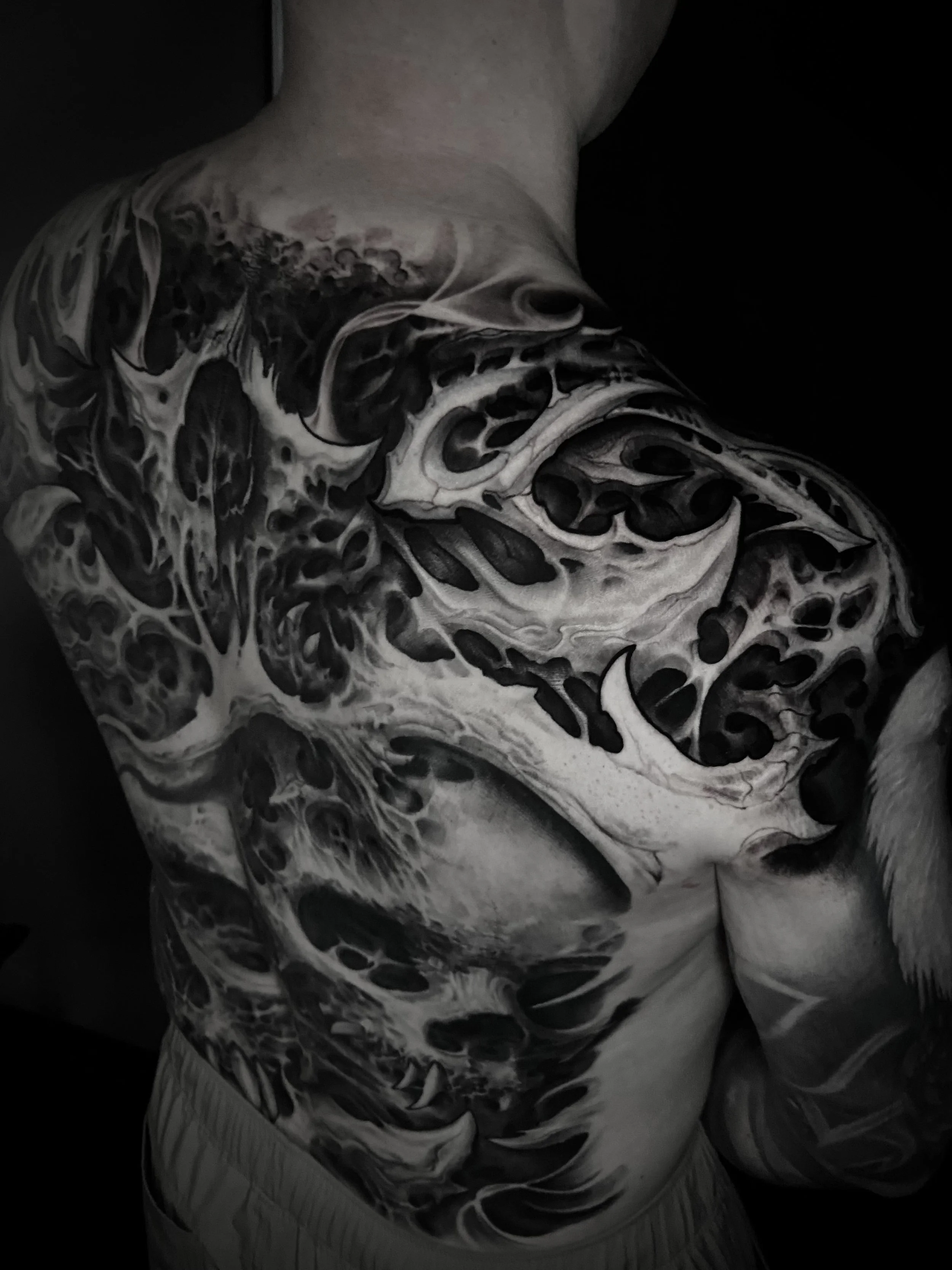 Black and white tattoo of a dragon on a person's shoulder and chest.