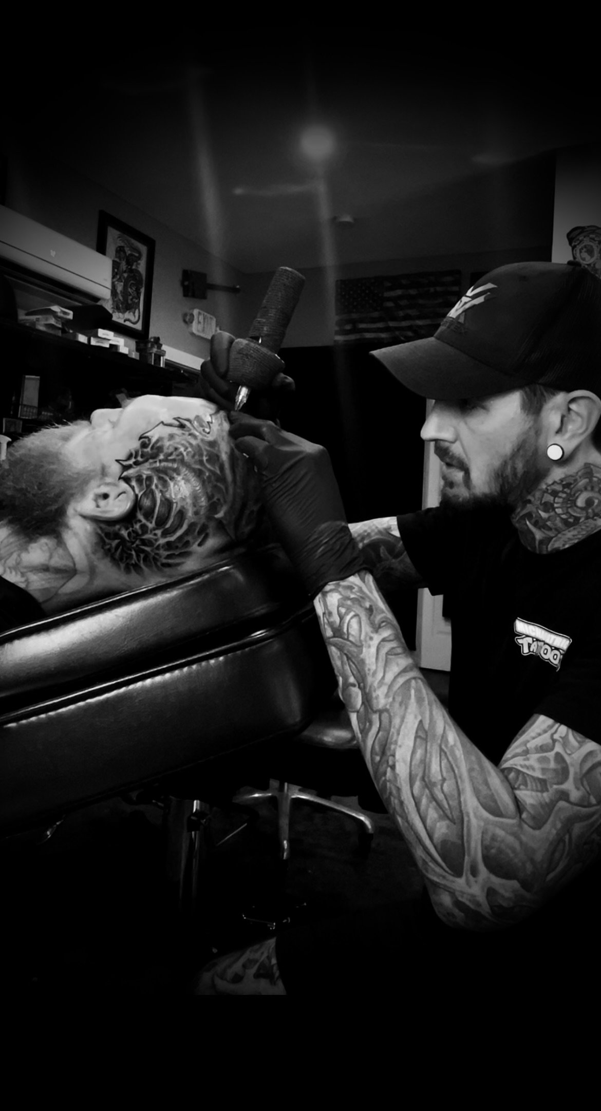 Tattoo artist working on a client in a tattoo studio, black and white photo