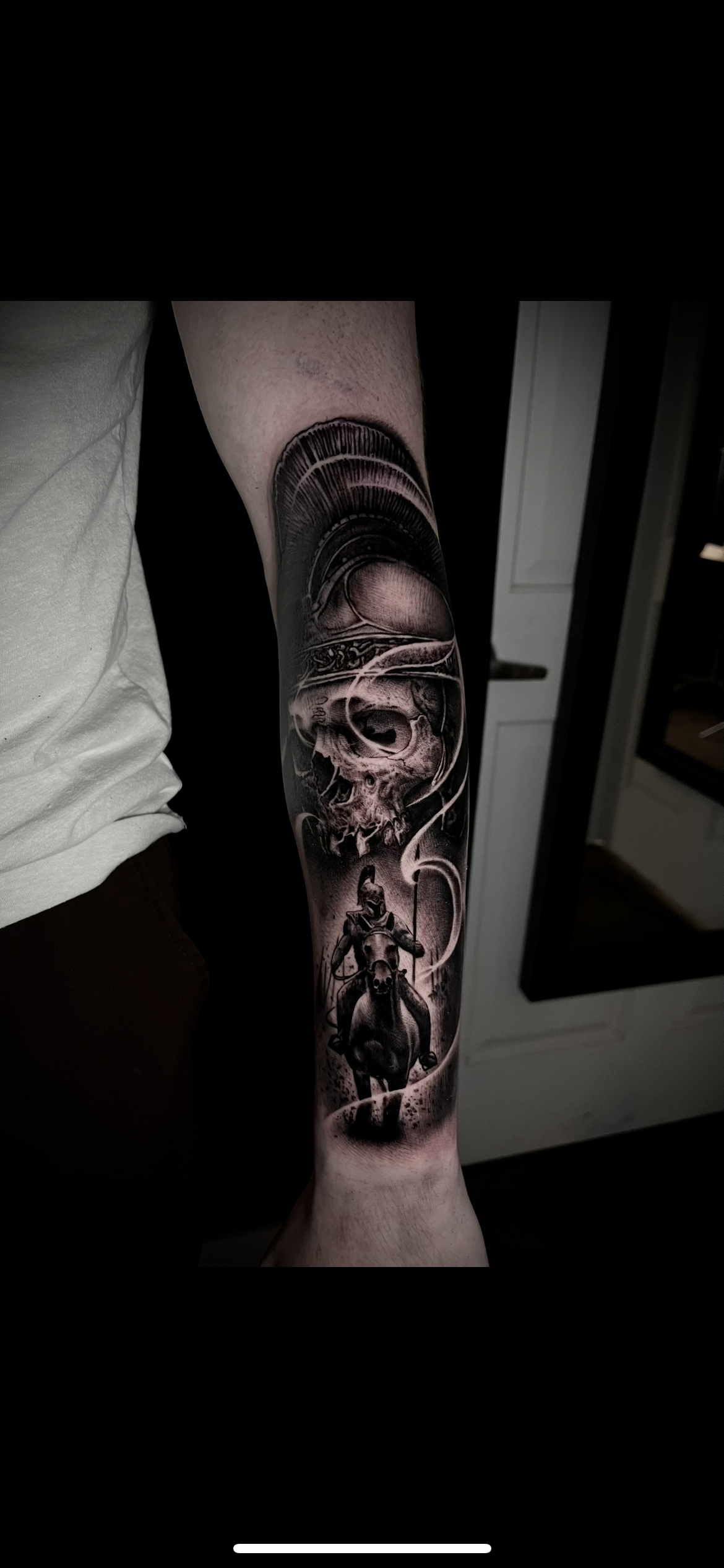 Black and gray tattoo sleeve featuring a Roman helmet with feathers, a skull, and a person riding a horse with a spear.