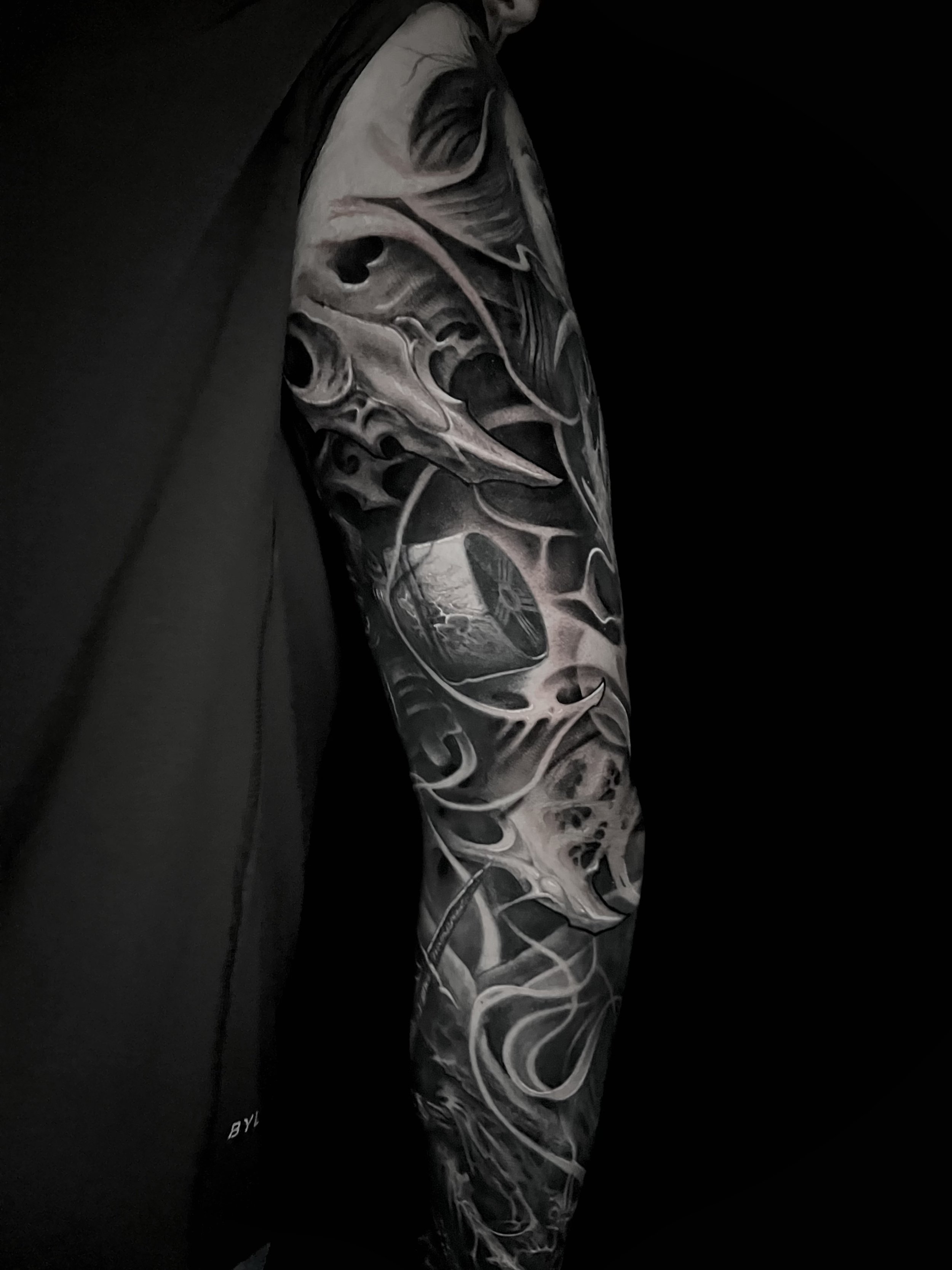 Black and white detailed skull tattoo sleeve on a person's arm.