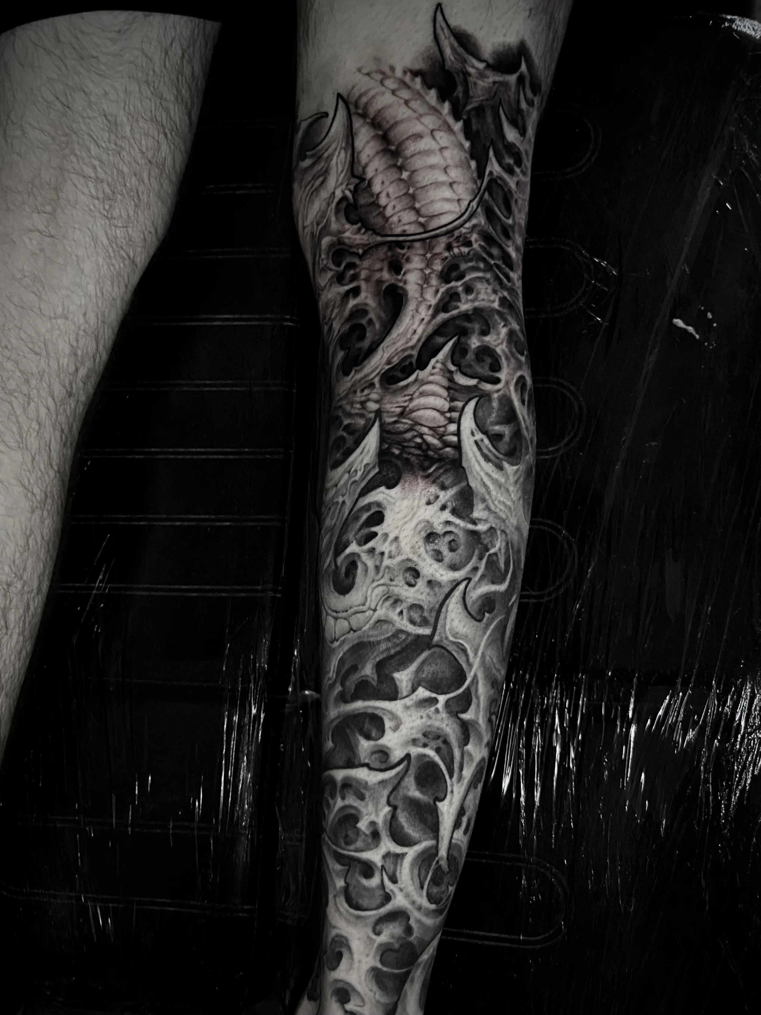 Detailed black and gray tattoo of a dragon on a person's arm.