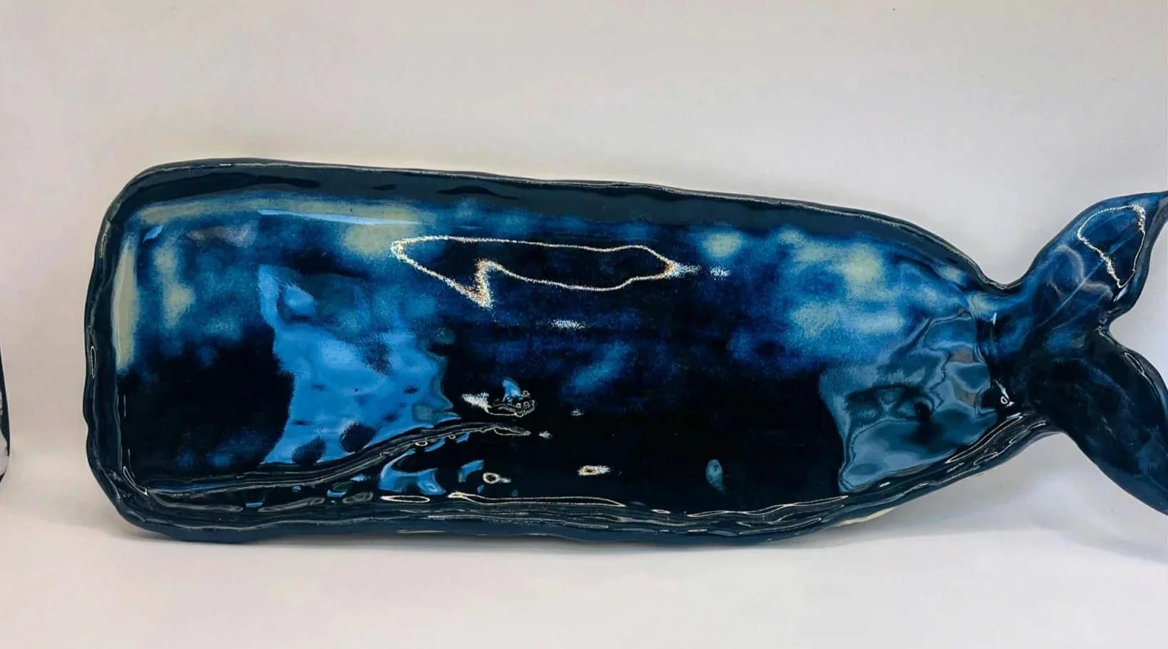 Dark blue ceramic whale-shaped plate with a glossy glaze.