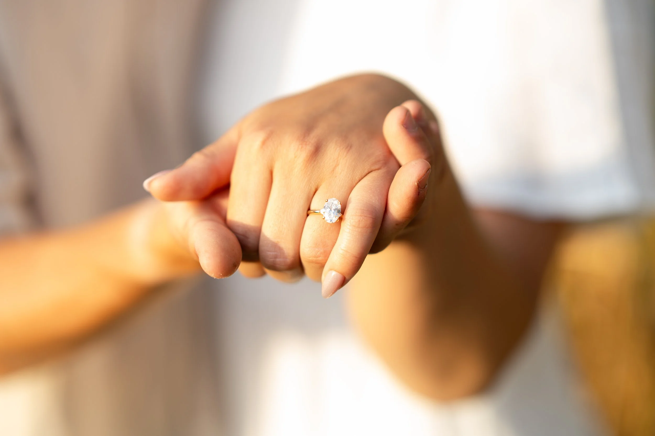 Close-up of a hand with an engagement ring featuring a large round diamond.