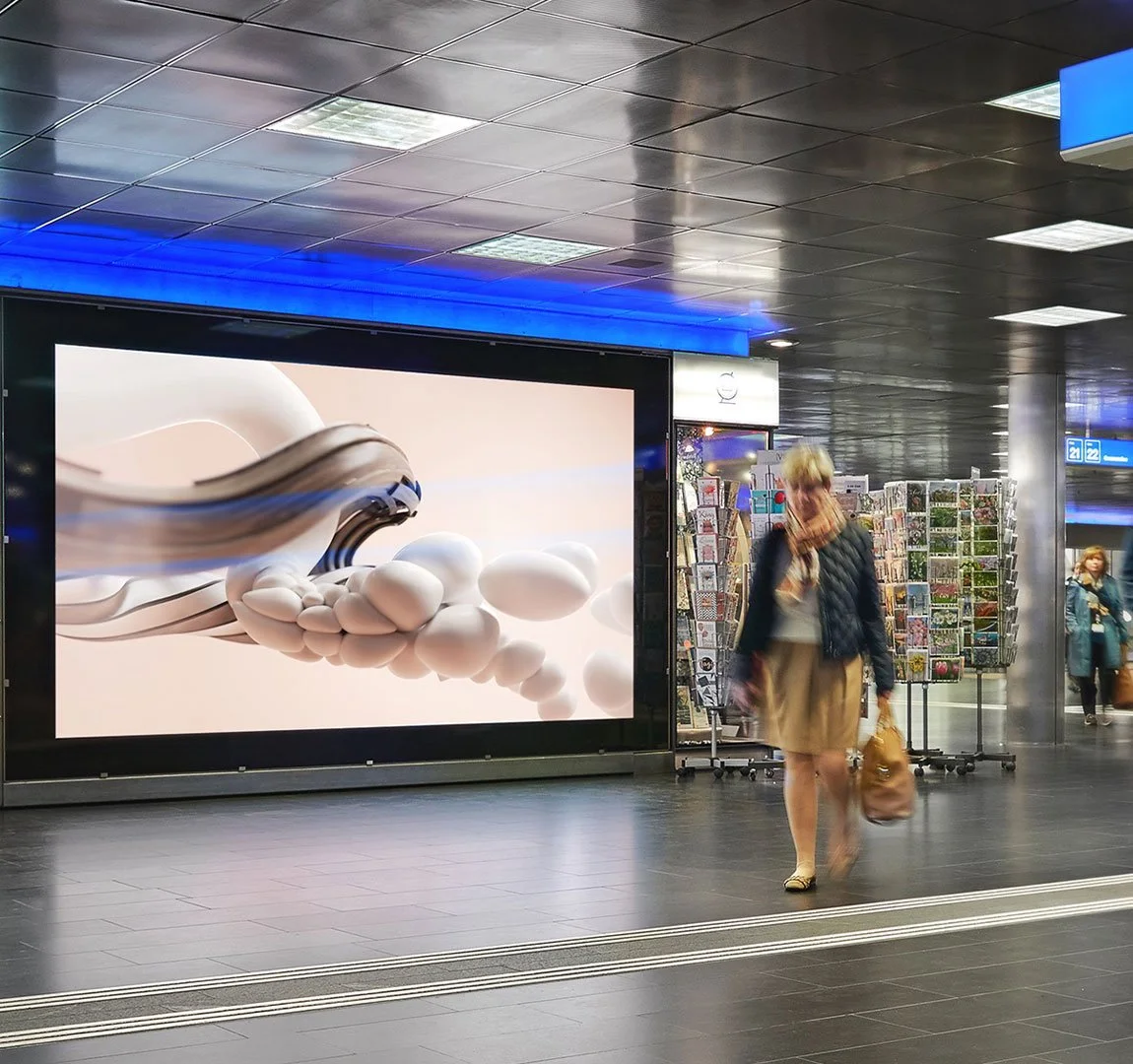 Bauarena, Frau läuft in U-Bahnhof mit digitaler Werbetafel und Kiosk mit Postkarten.