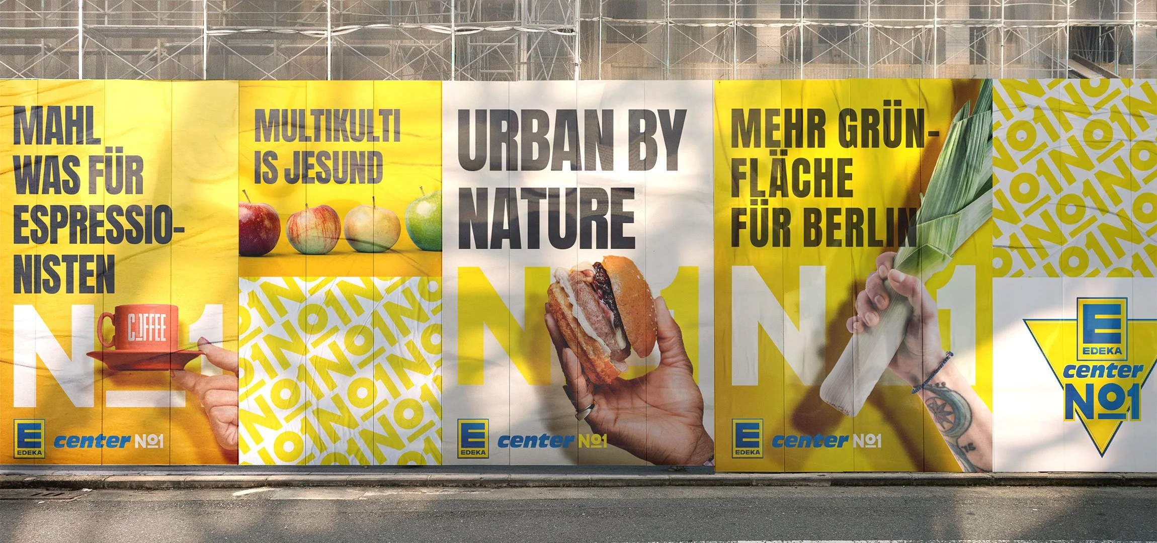 EDEKA No1 - Baustellenkommunikation für einen Supermarkt mit Slogans und Bildern von Lebensmitteln, darunter Äpfel, ein Burger und eine Person, die ein Bananenblatt hält. Das Design ist in Gelb, Weiß und Blau gehalten.