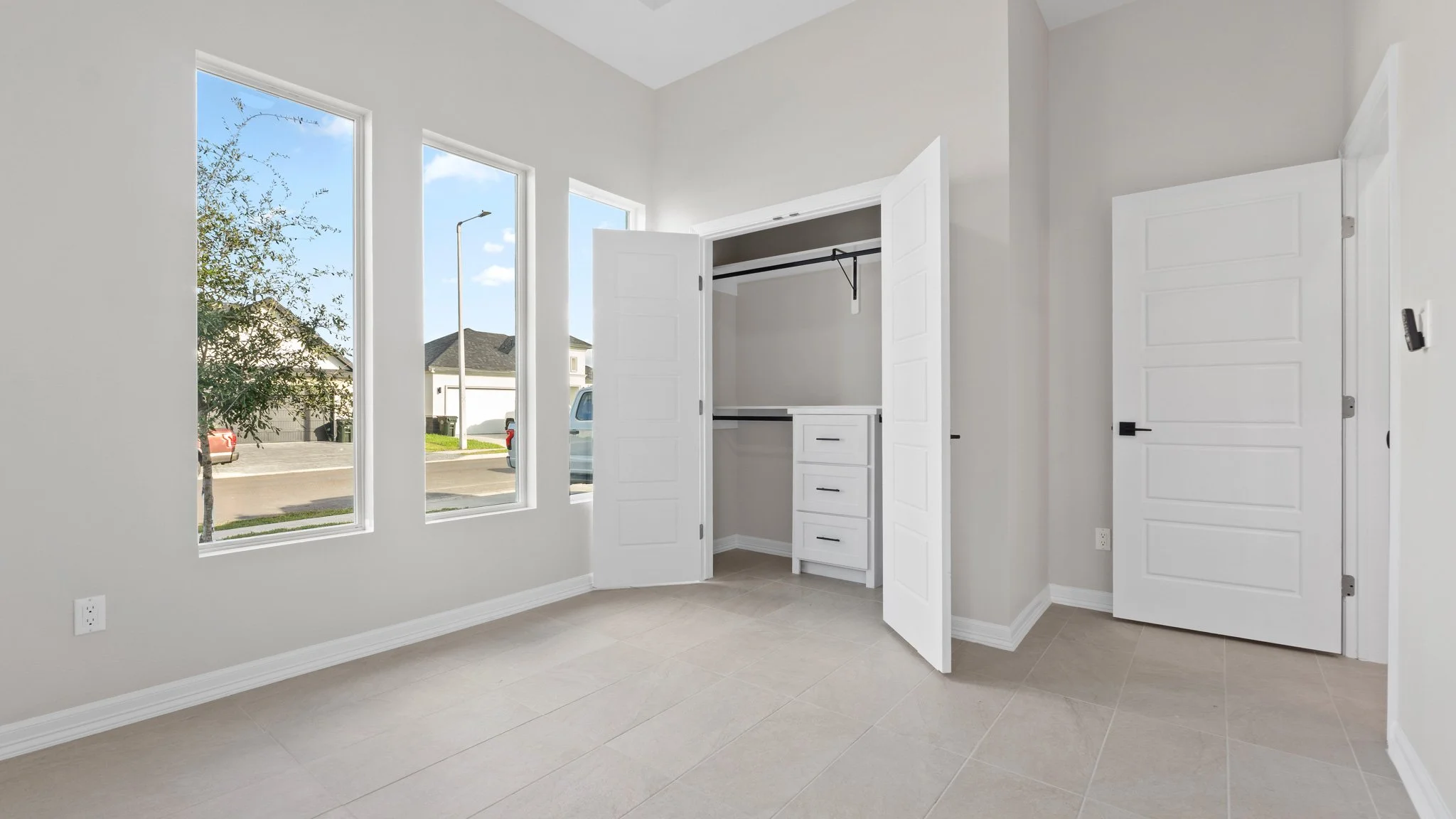 Habitación vacía con ventanas grandes y armario empotrado con puertas dobles abiertas.