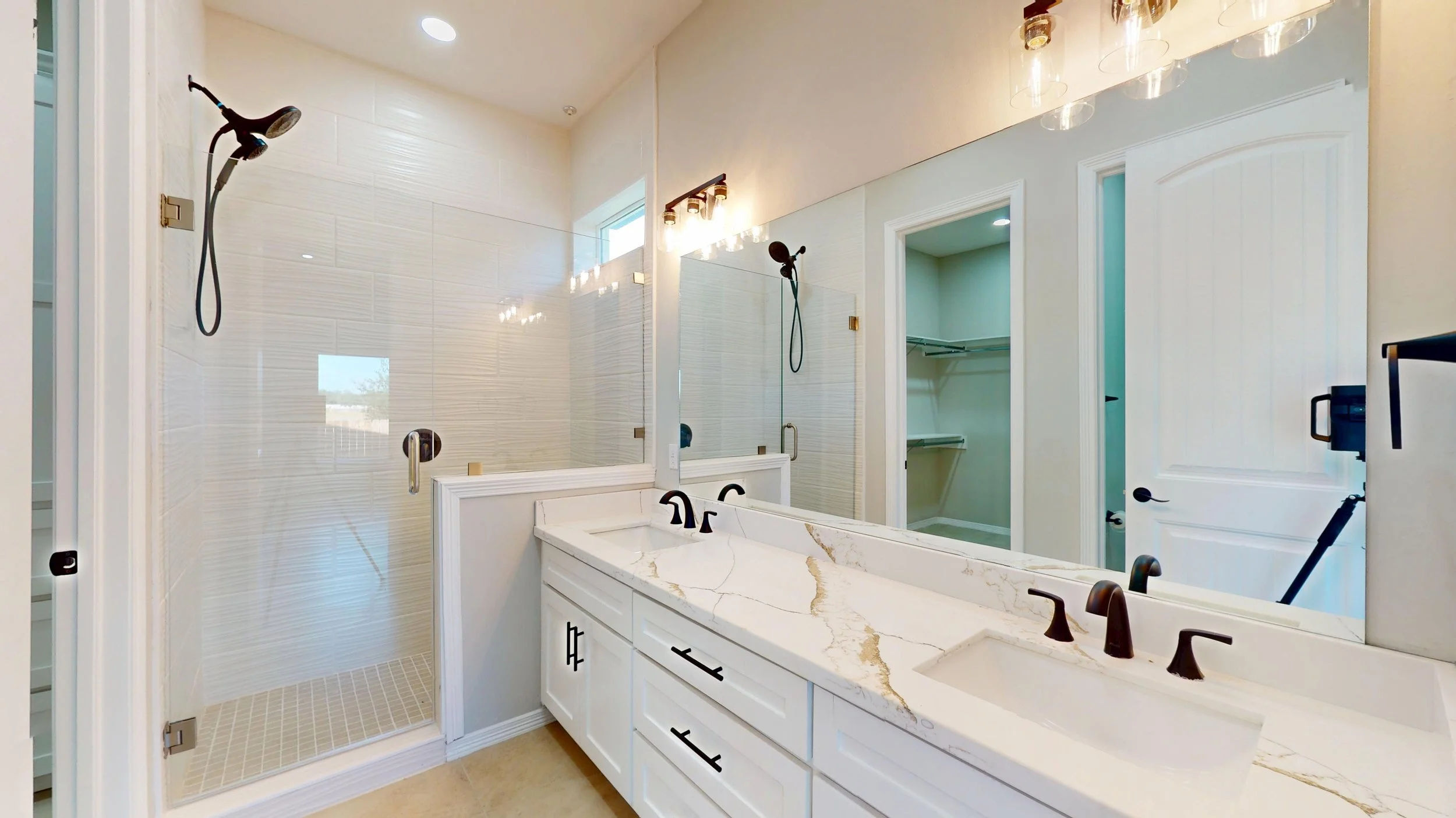 Baño con ducha de cristal, lavabo de mármol y espejo grande.