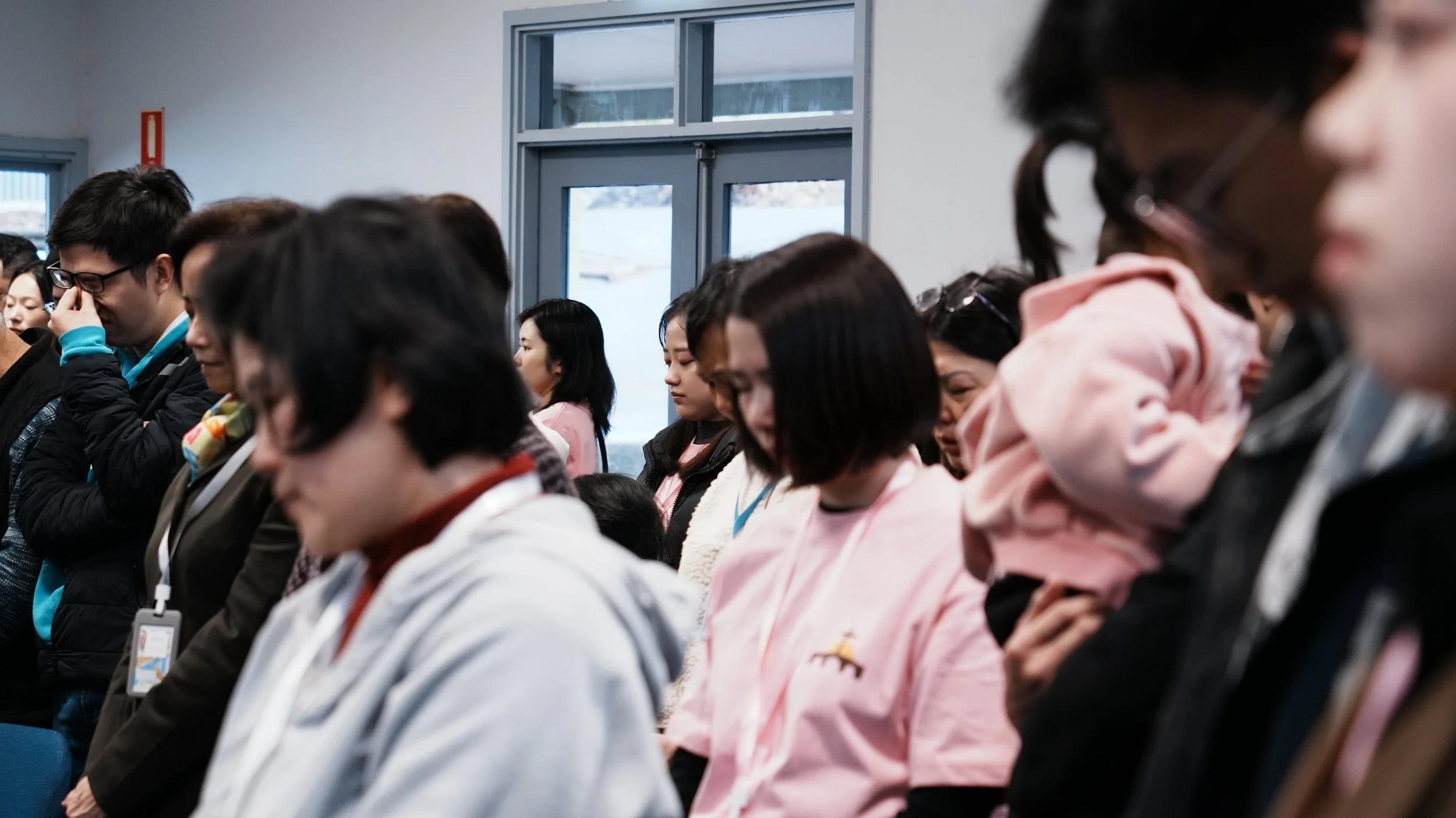 People standing, with their heads bowed in prayer.