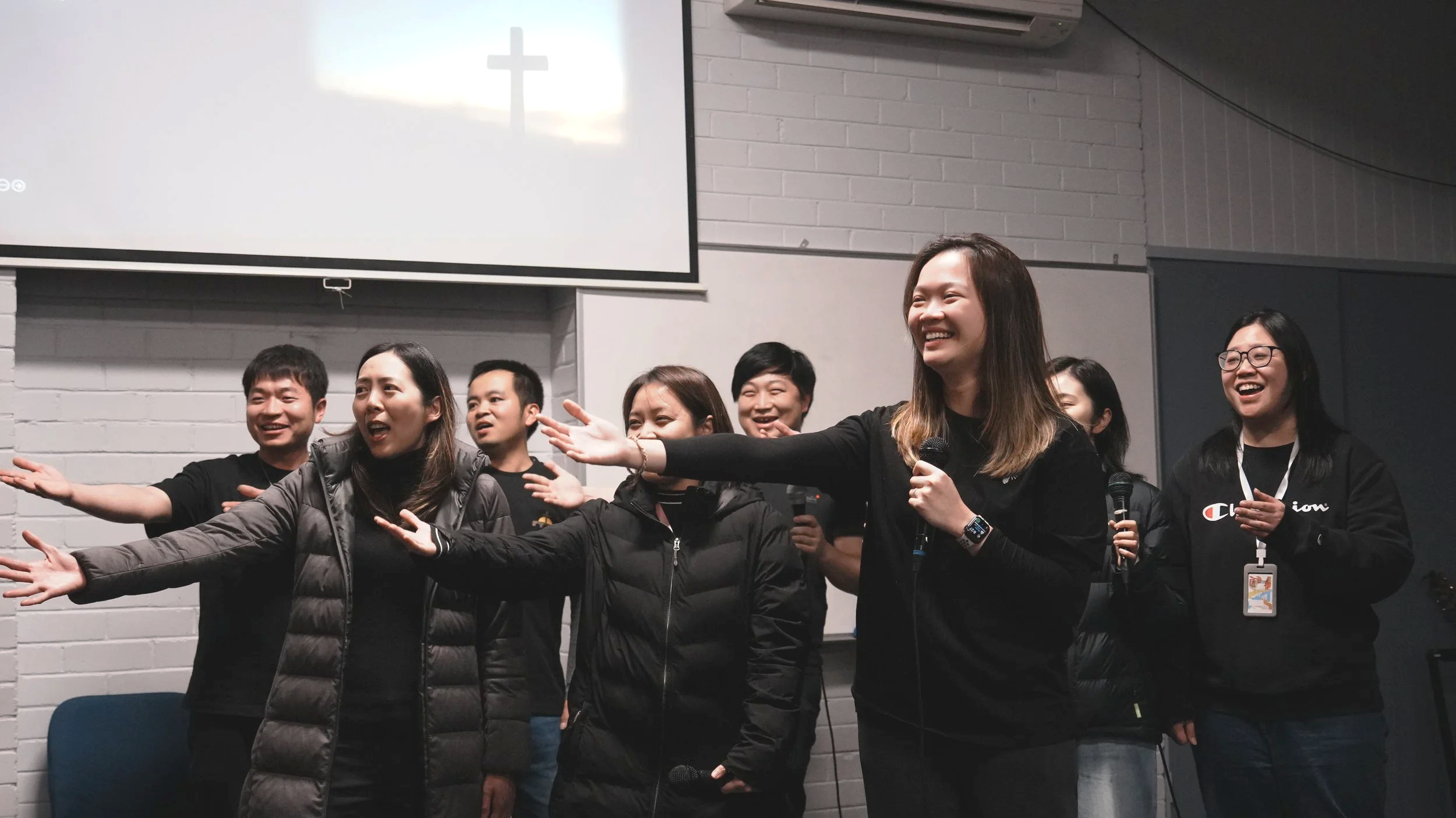 A group of people gesturing to someone out of the image.