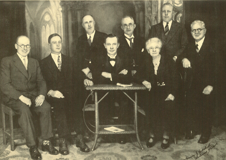Eight people, formally dressed, posing for a portrait