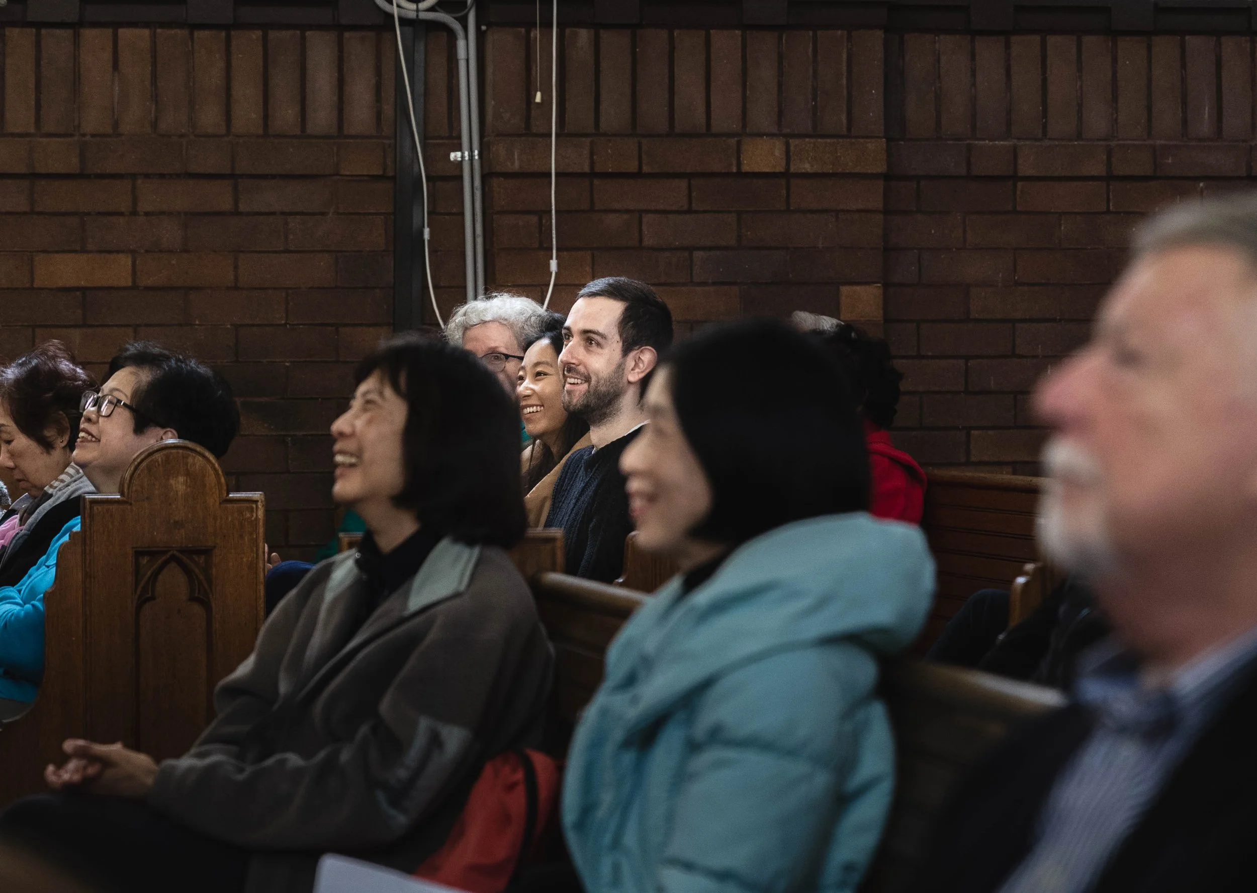 People sitting in pews, laughing at something that's just been said.