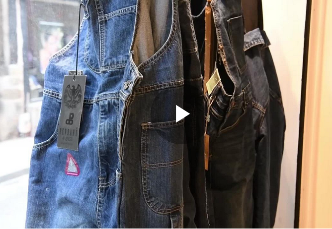 Pantalons en denim de différentes couleurs suspendus dans un magasin.