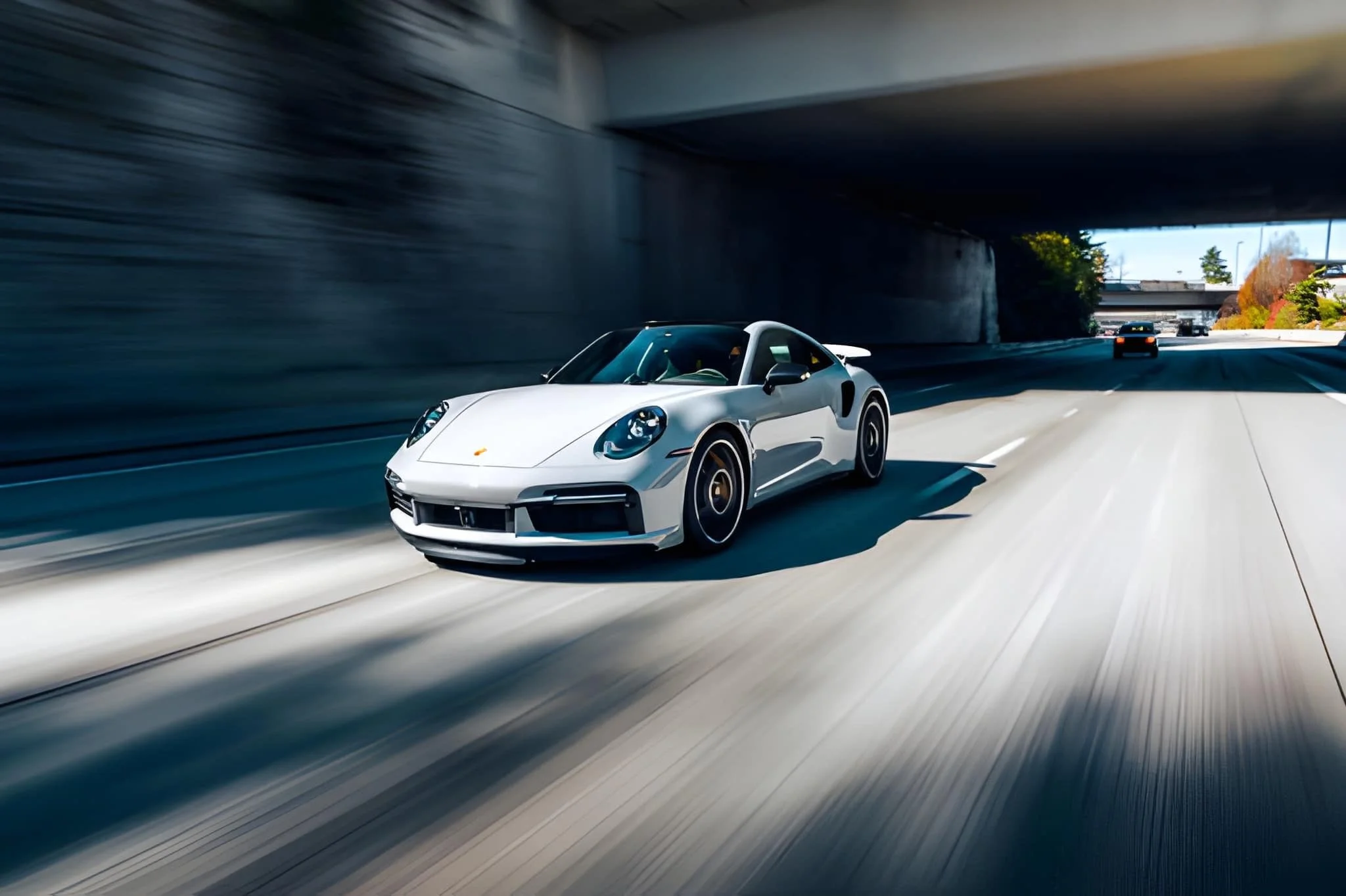 Ein weißer Porsche 911 fährt auf einer Autobahn durch einen Tunnel.