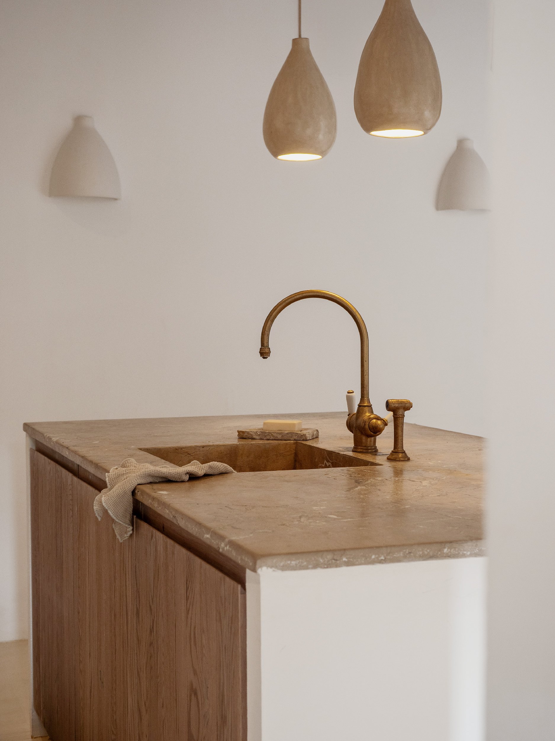 Kitchen with a stone countertop, brass faucet, and three hanging pendant lights