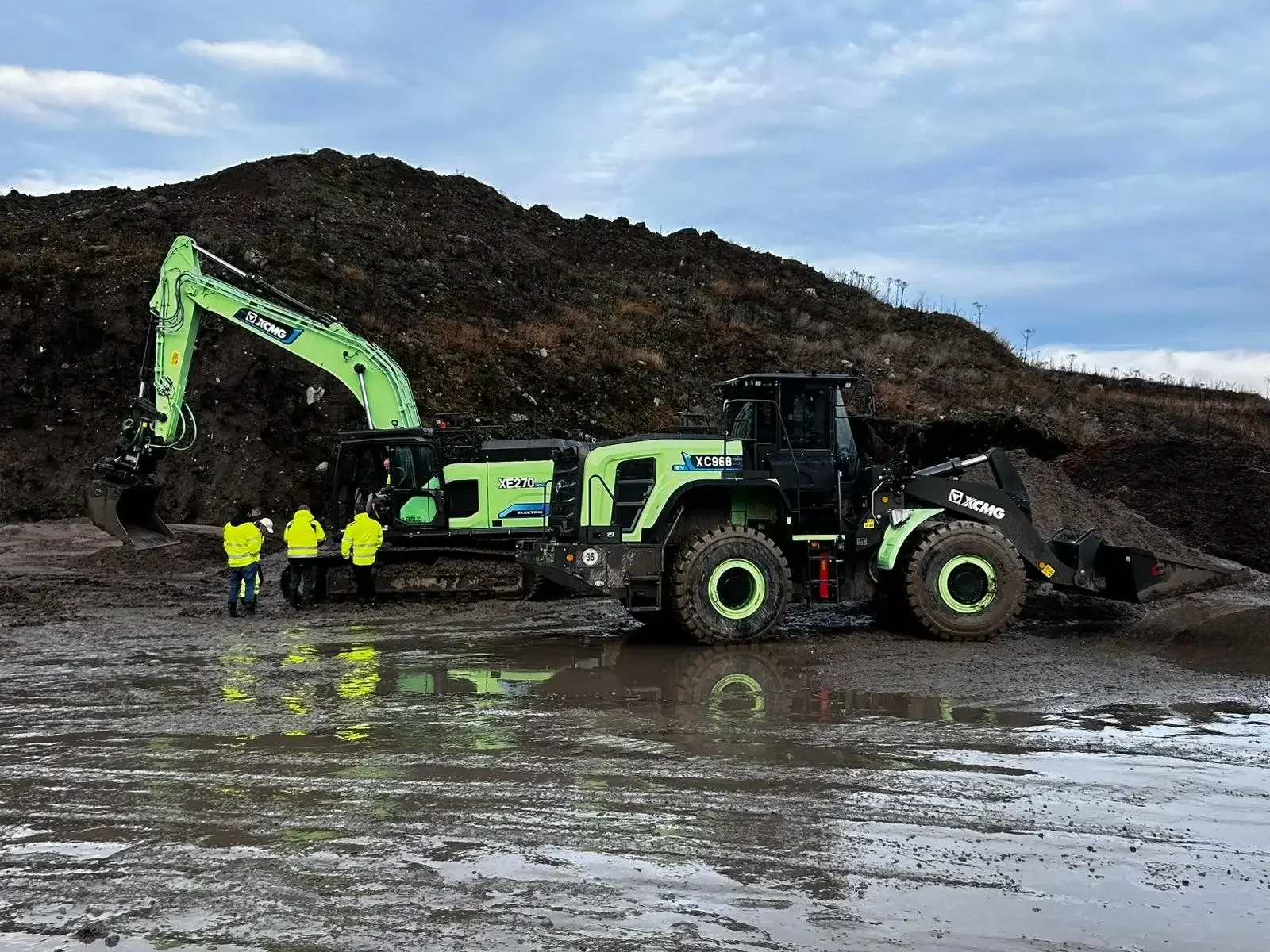 Elektrisk grävmaskin och traktor ute