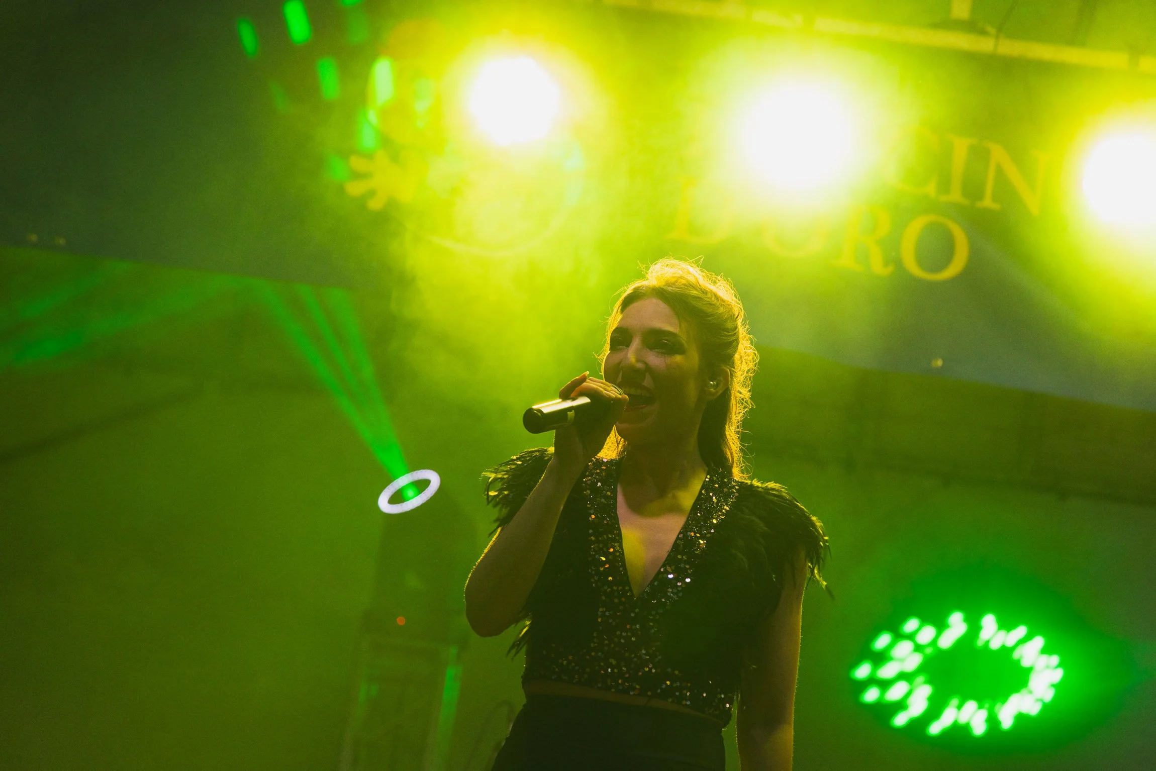Una donna canta sul palco, illuminata da luci verdi e gialle, durante una performance.

© Alessandro Holneider