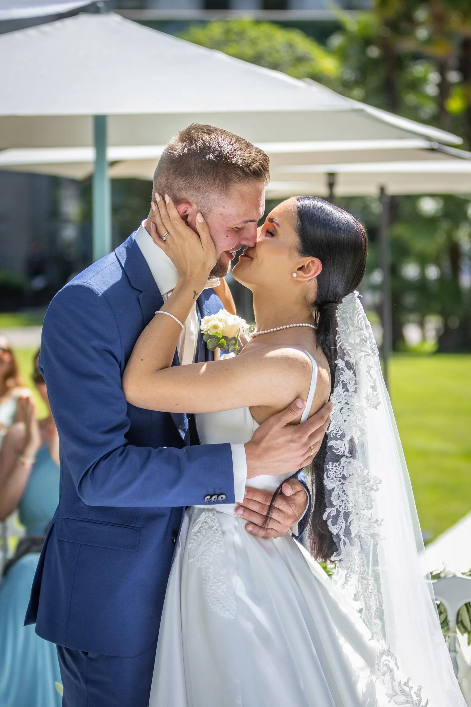 Una coppia di sposi si bacia durante il matrimonio all'aperto.