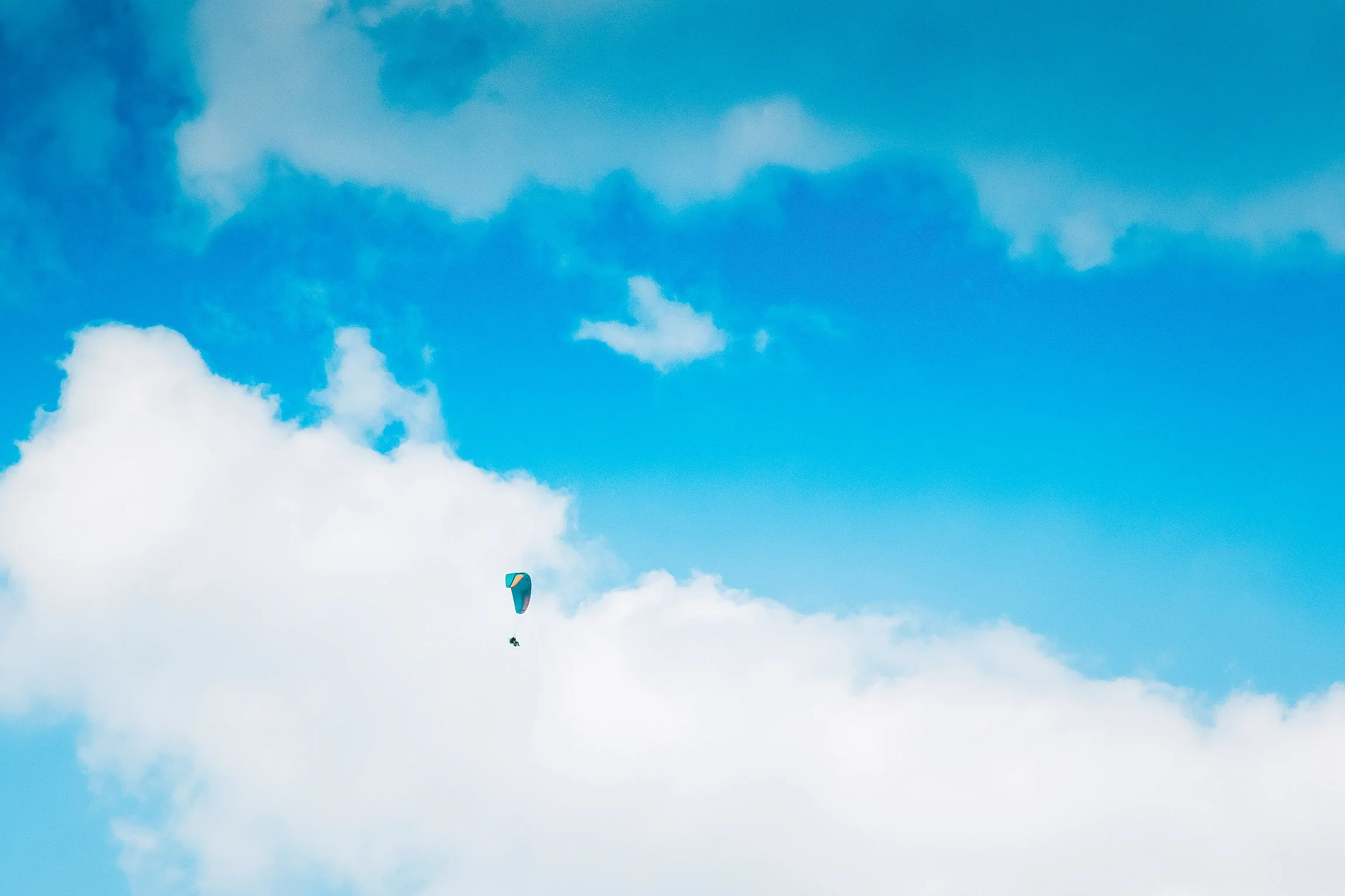 Un parapendio che vola nel cielo con nuvole bianche e cielo azzurro.

© Alessandro Holneider