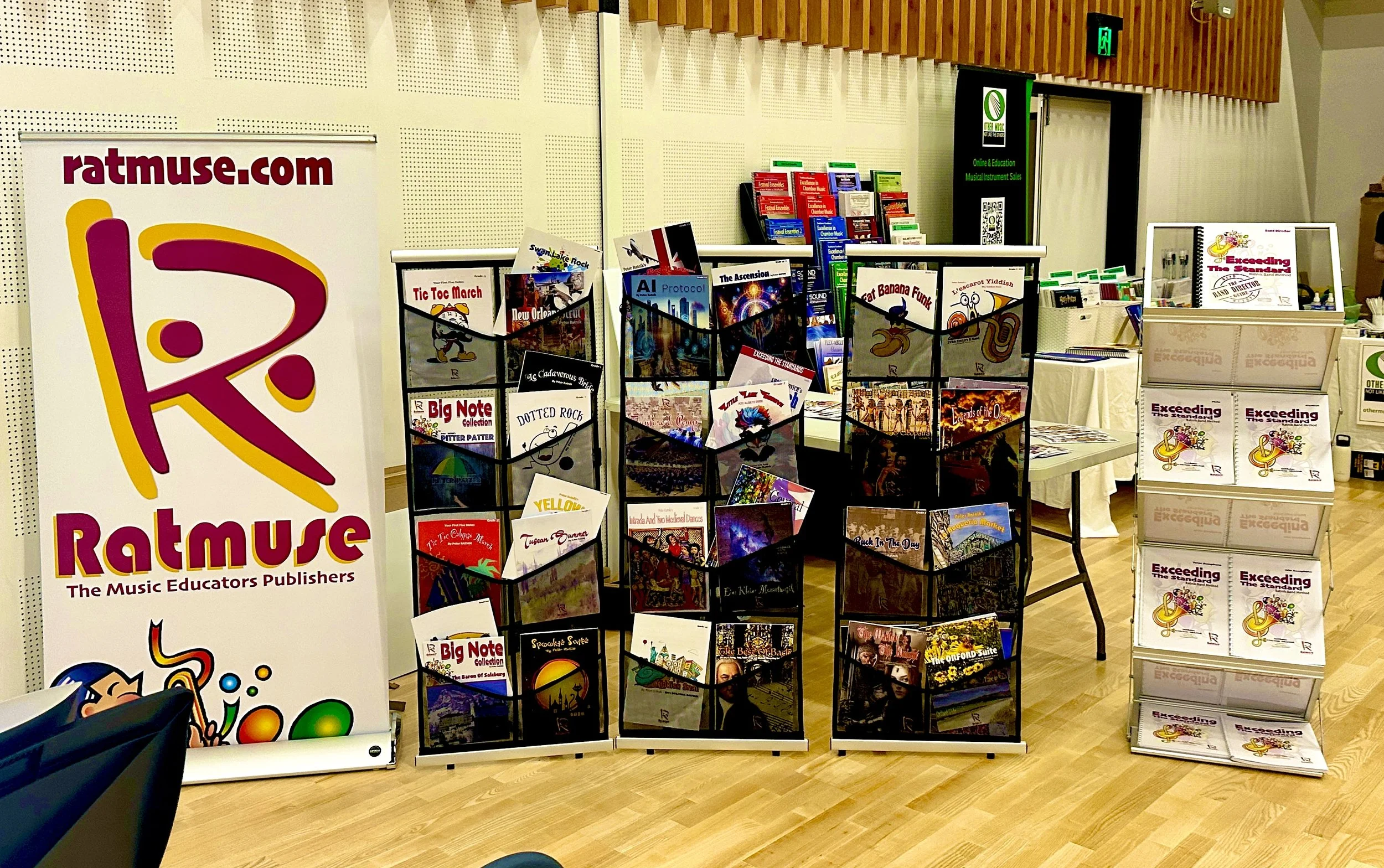 Display of music books and publications at a booth, with sign reading 'ratmuse.com' and tagline 'The Music Educators Publishers'.  Featuring Exceeding the Standards Band Method books
