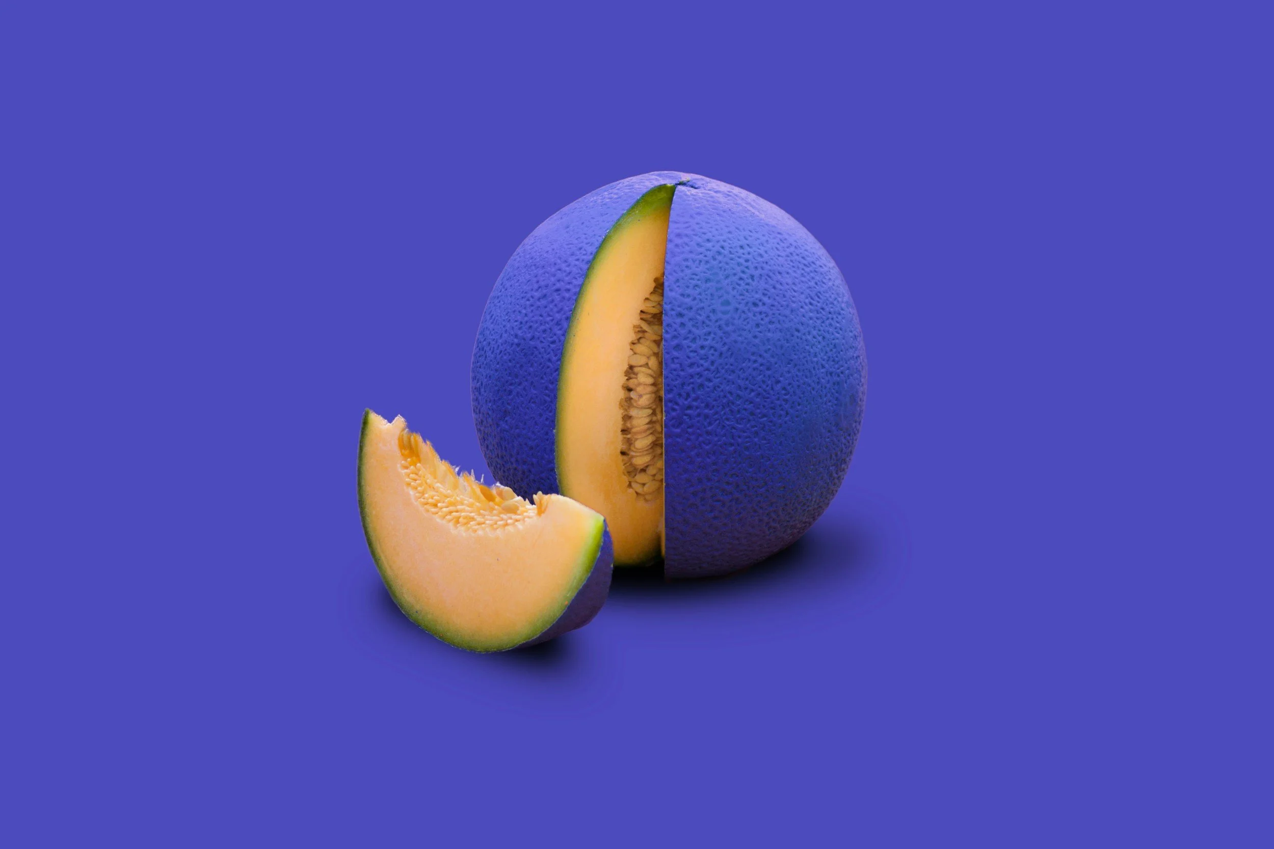 A whole cantaloupe with blue rind and a slice cut out and placed in front of it, on a blue background.