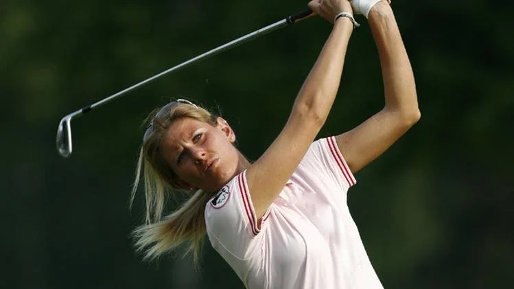 Una donna che gioca a golf, sta attraversando il colpo con un bastone da golf in un campo.