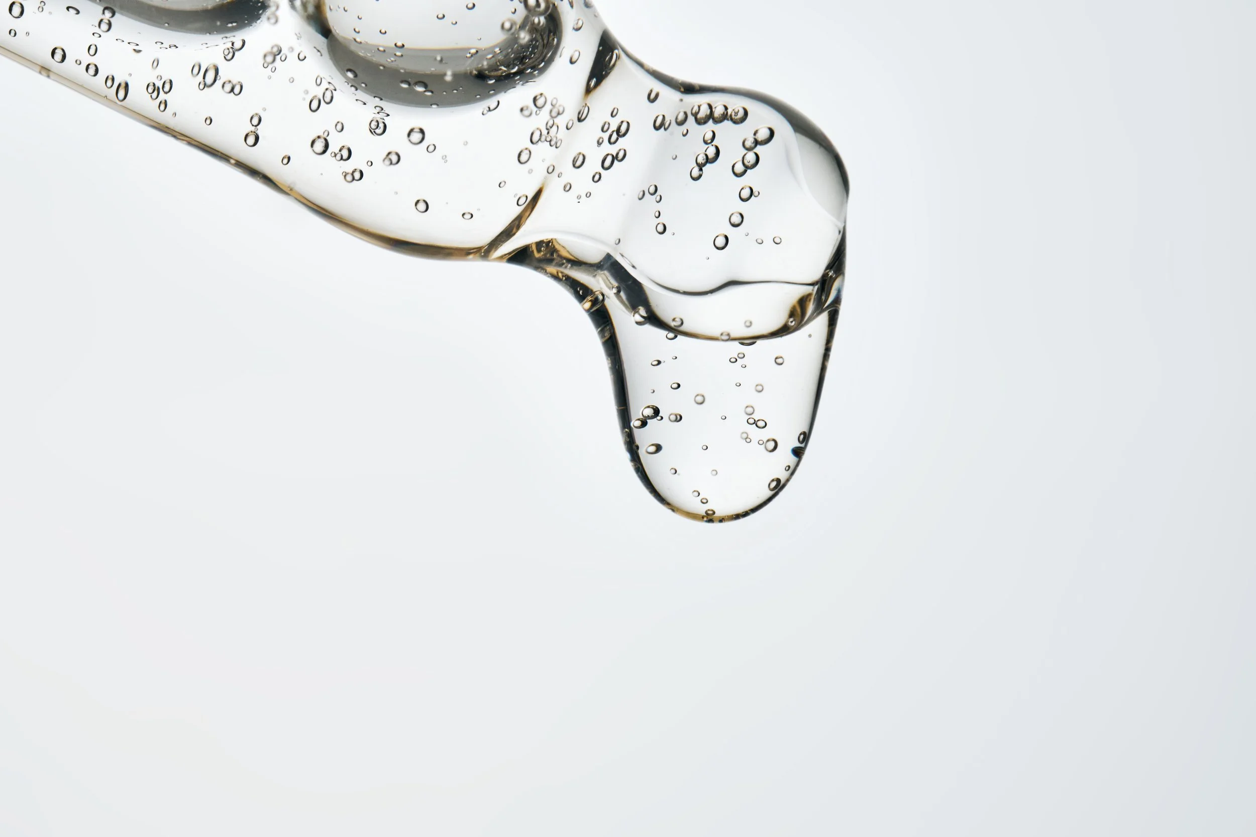 A close-up of a cosmetic pipette dispensing serum creating bubbles