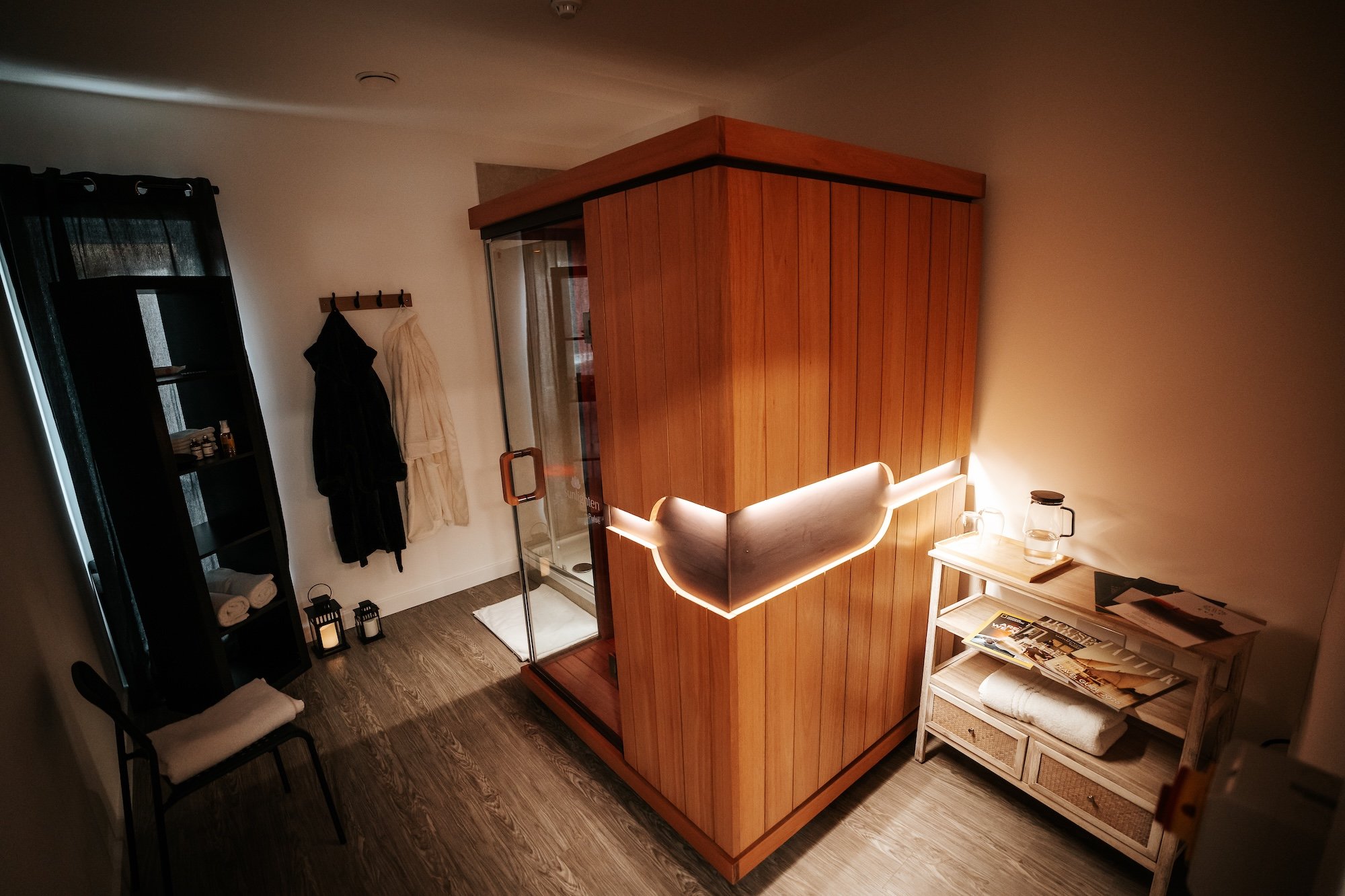 An infrared sauna in sauna treatment room, with dressing gowns in background