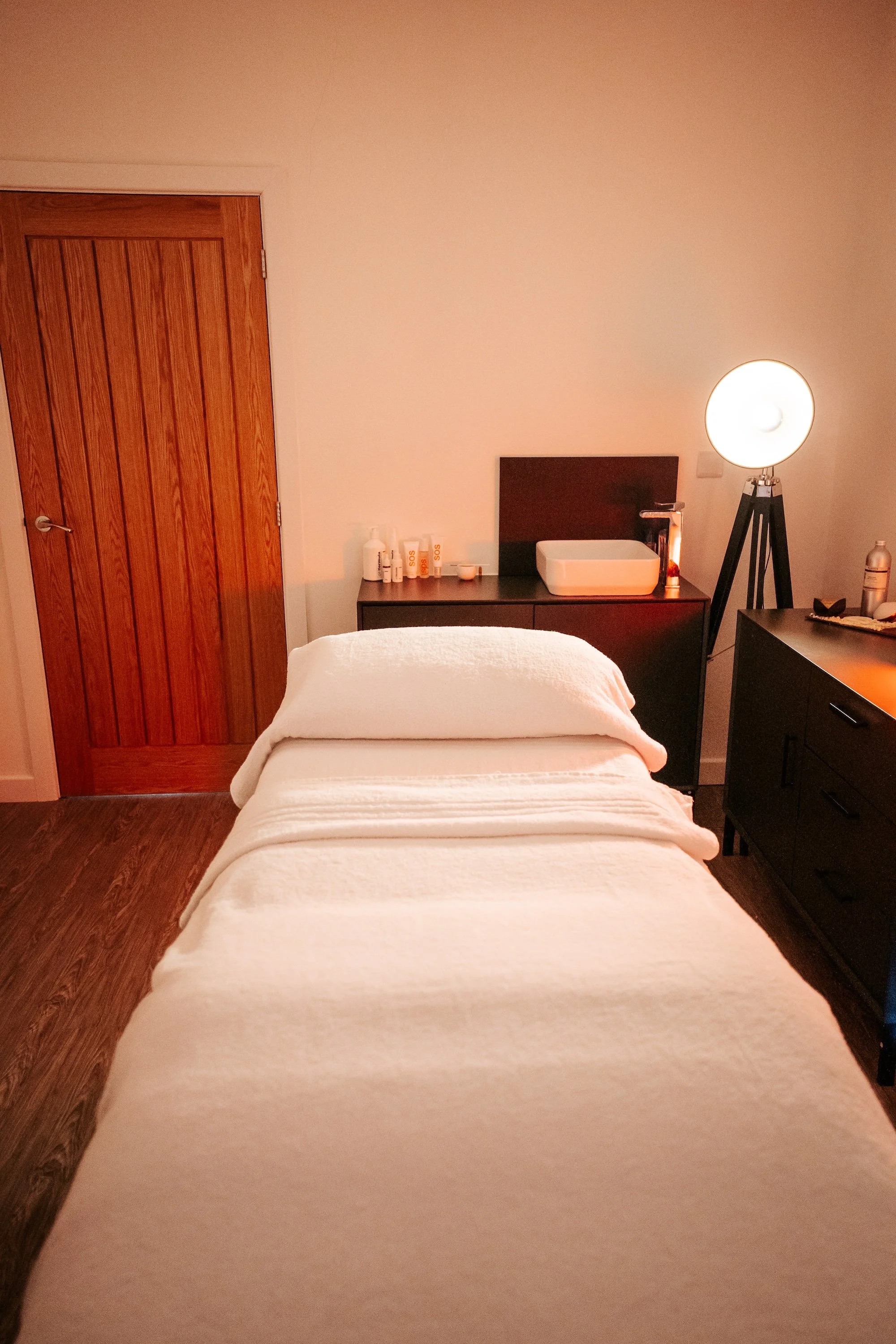 A treatment bed covered with white towels in a dimly lit treatment room