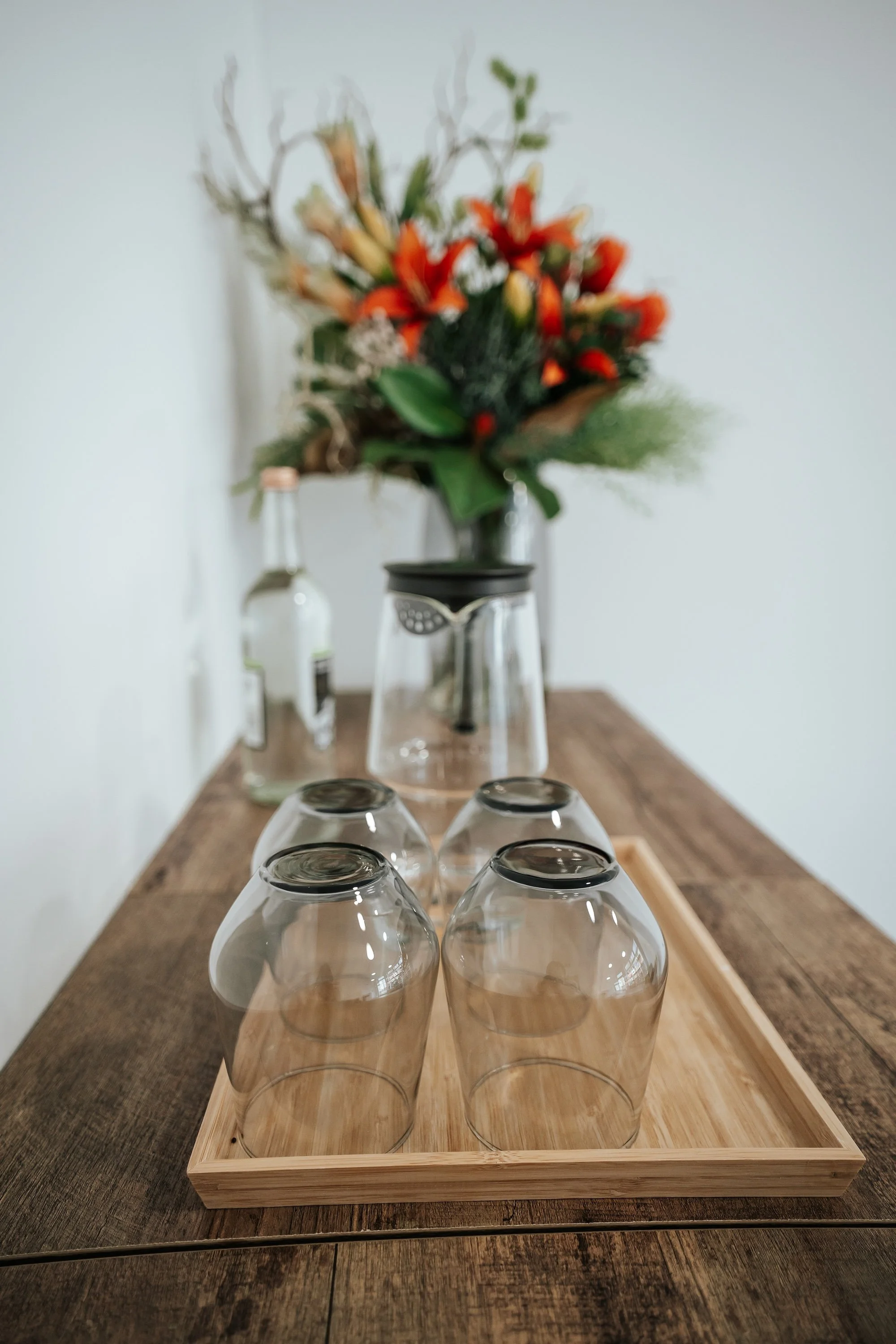 A sideboard with upside down tumblers, and flowers in the background