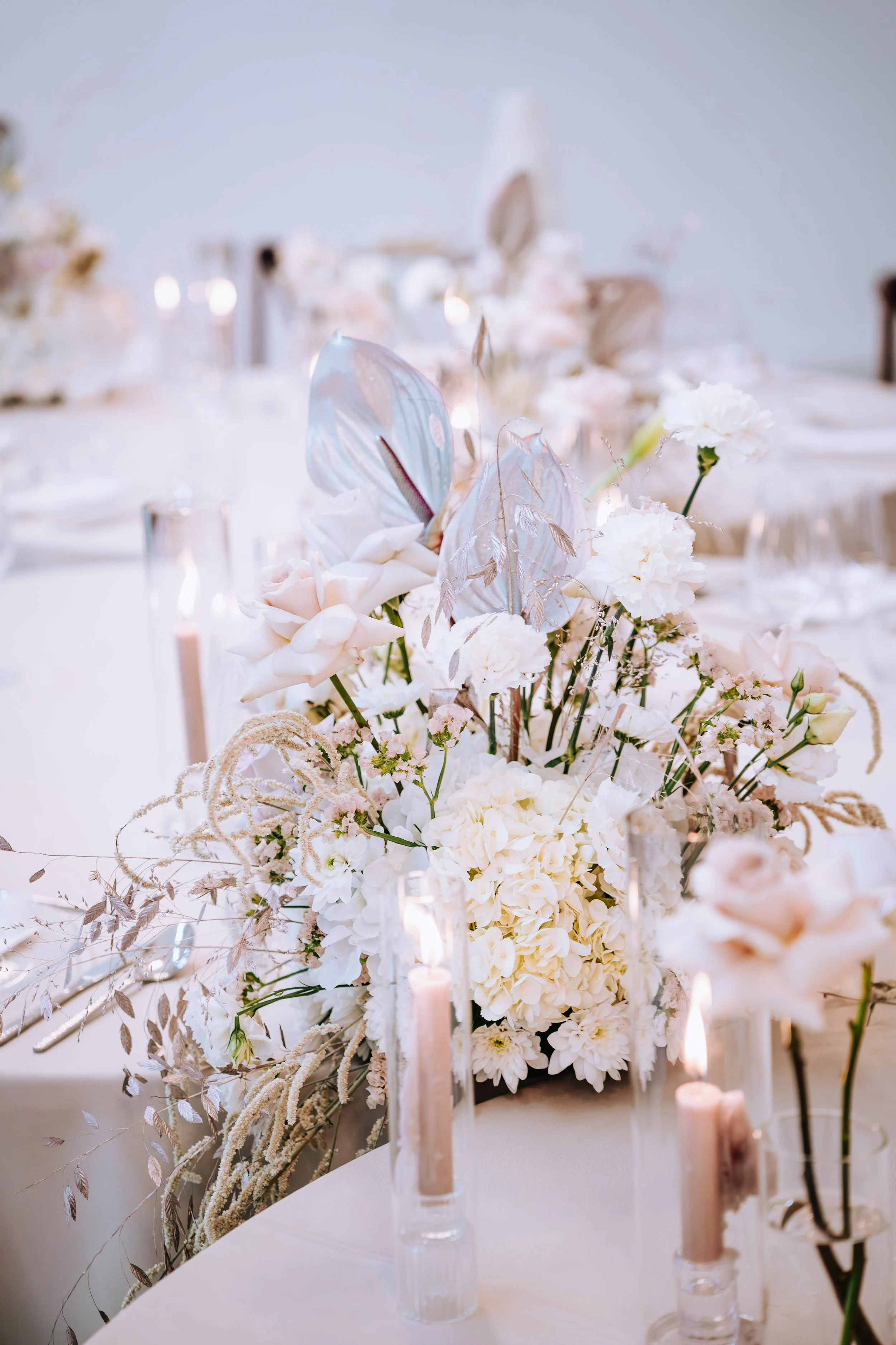 Elegante Tischdekoration mit weißen Blumen, Kerzen und Schmetterlingsdekoration auf einem hellen Tisch.