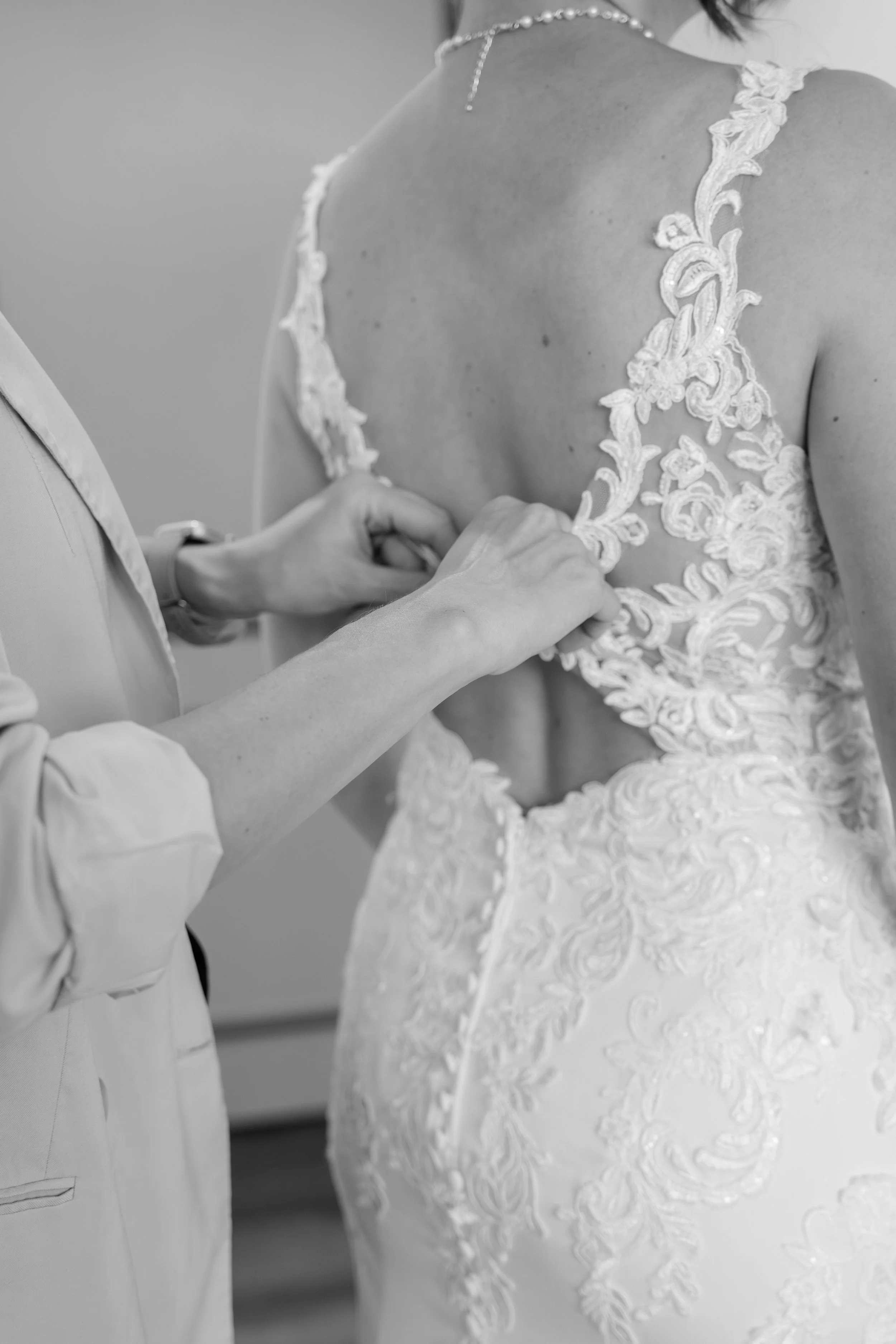 Eine Braut wird bei der Anprobe ihres Hochzeitskleides geholfen.