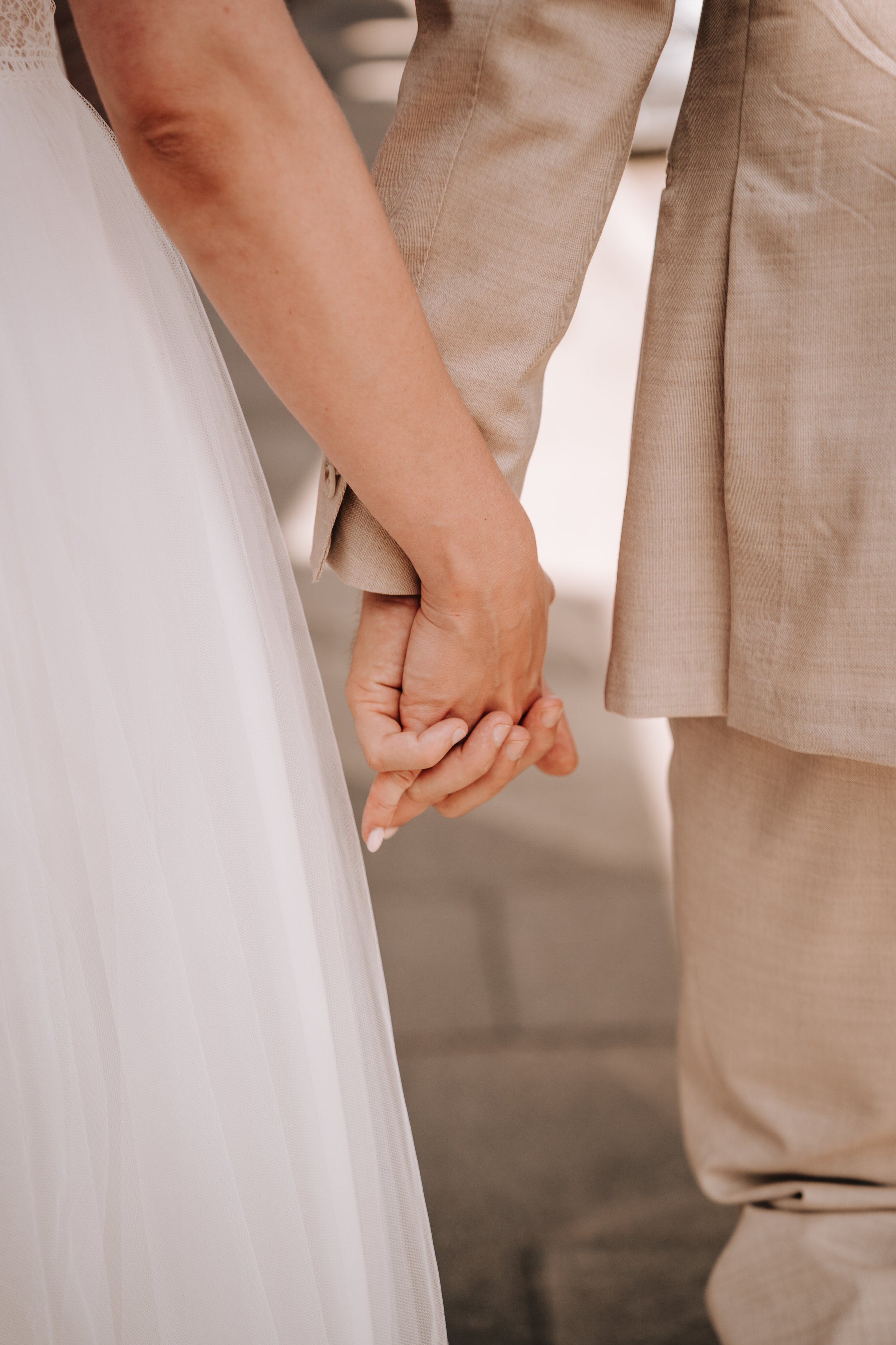 Nahaufnahme von zwei Menschen, die sich an den Händen halten, bei einer Hochzeitszeremonie.