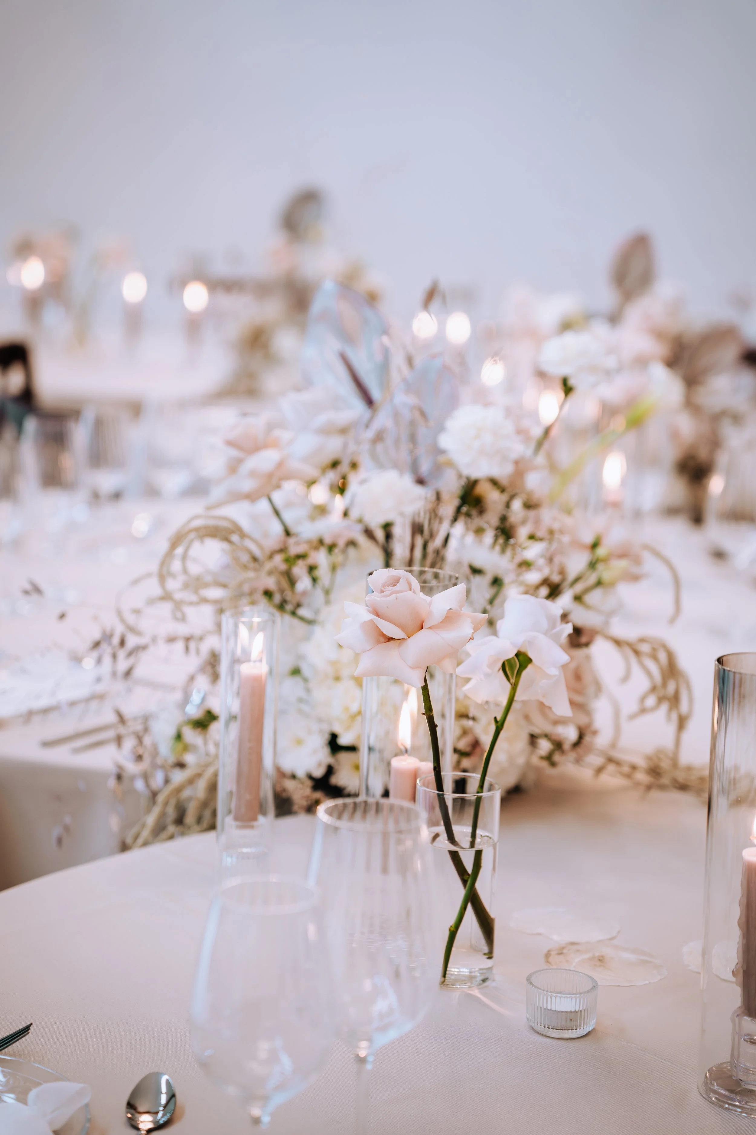 Eleganter Blumenstrauß aus weißen und pastellfarbenen Blumen mit Kerzen auf einem festlich gedeckten Tisch bei einer Veranstaltung