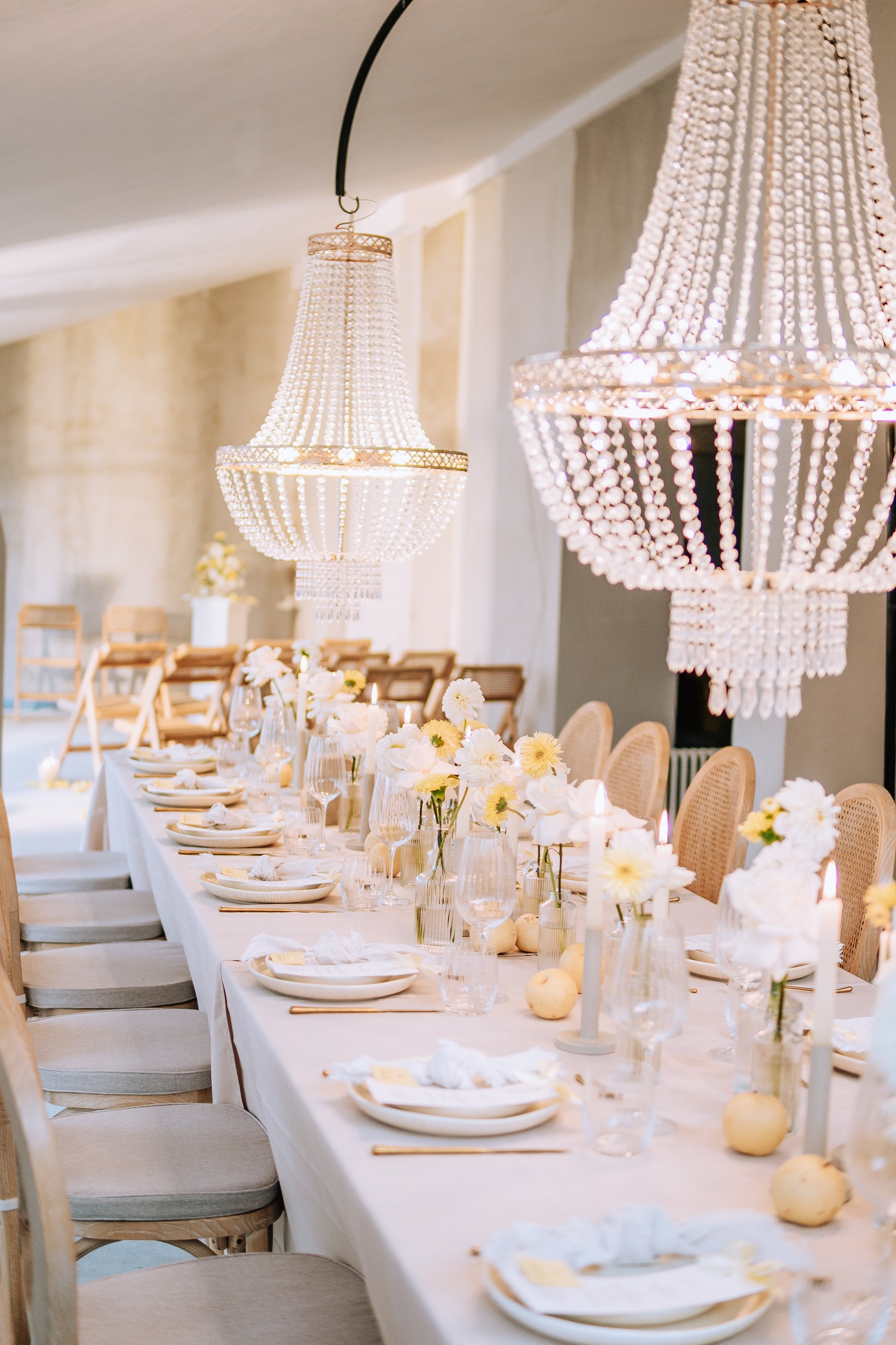 Eleganter festlicher Raum mit langem Tisch, gedeckt mit weißen Tafel sett, Kerzen, Blumen und Kristallleuchtern.