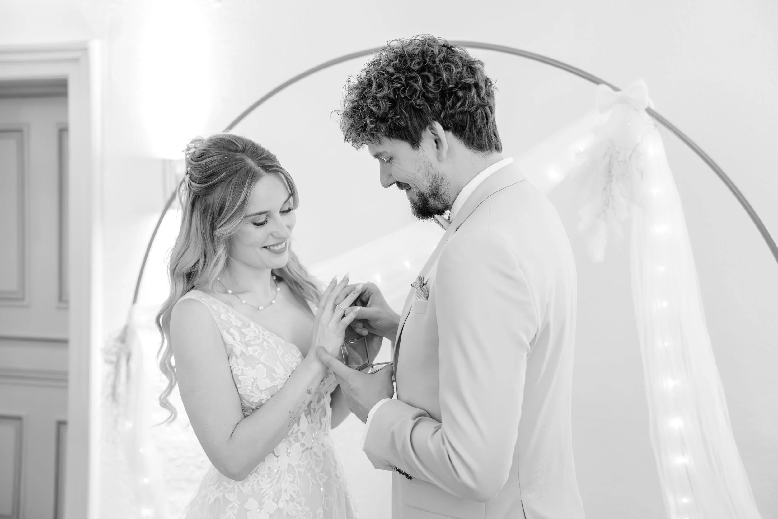 Ein Brautpaar tauscht Ringe während ihrer Hochzeitszeremonie in einem festlich dekorierten Raum.