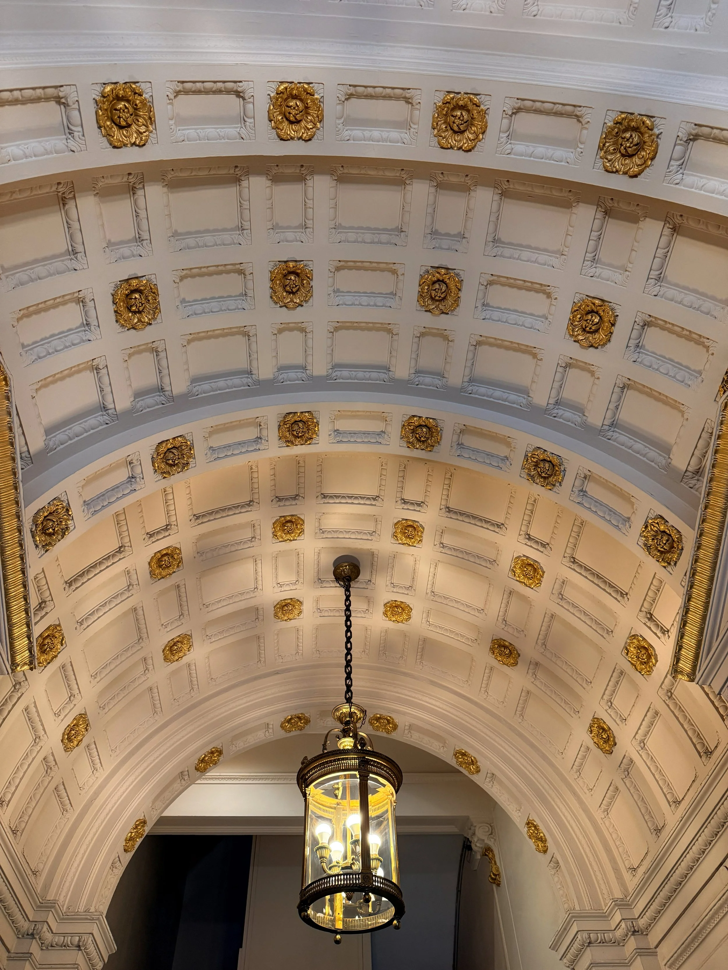 Techo decorado con molduras blancas y detalles dorados.