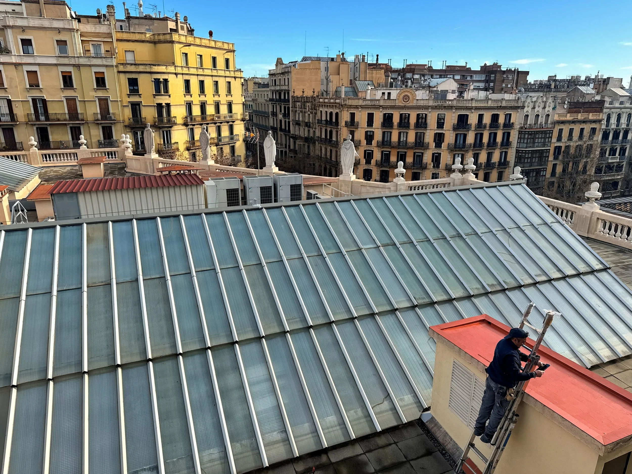 Vista de techos de edificios en una ciudad, con un técnico en la azotea ajustando antenas.