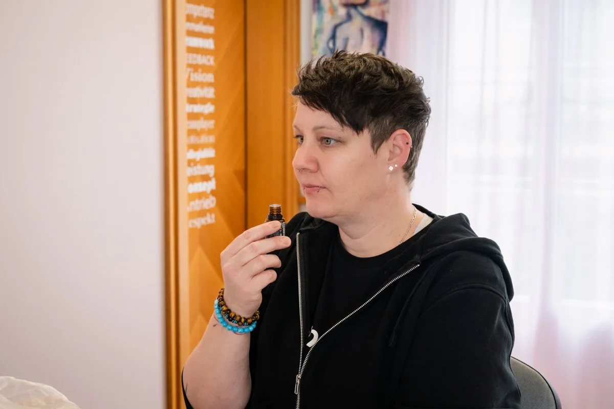 Eine Frau mit kurzen schwarzen Haaren hält eine Flasche mit ätherischem Öl in der Hand.