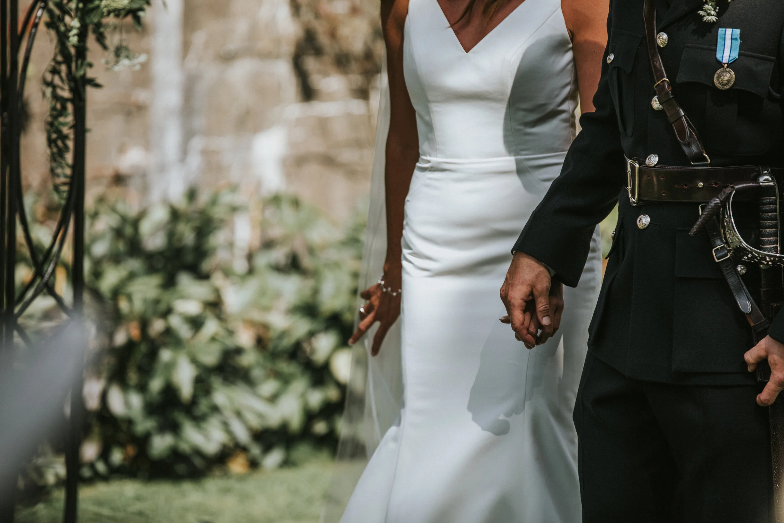 Close-up of a bride and a police officer holding hands at a wedding ceremony.