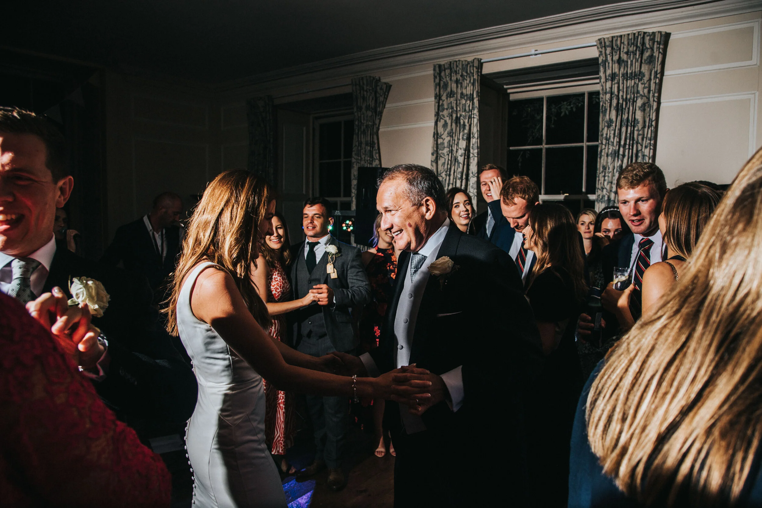 People dancing and socializing at a wedding reception in a decorated indoor venue.