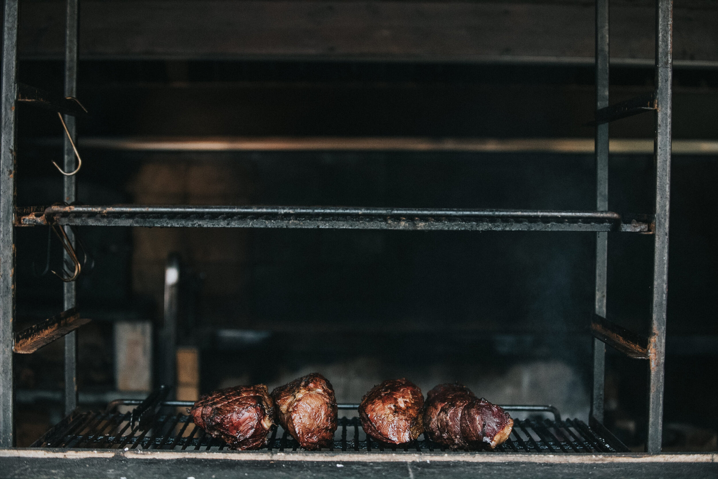 Four pieces of cooked meat on a grill in an oven, with empty racks above.